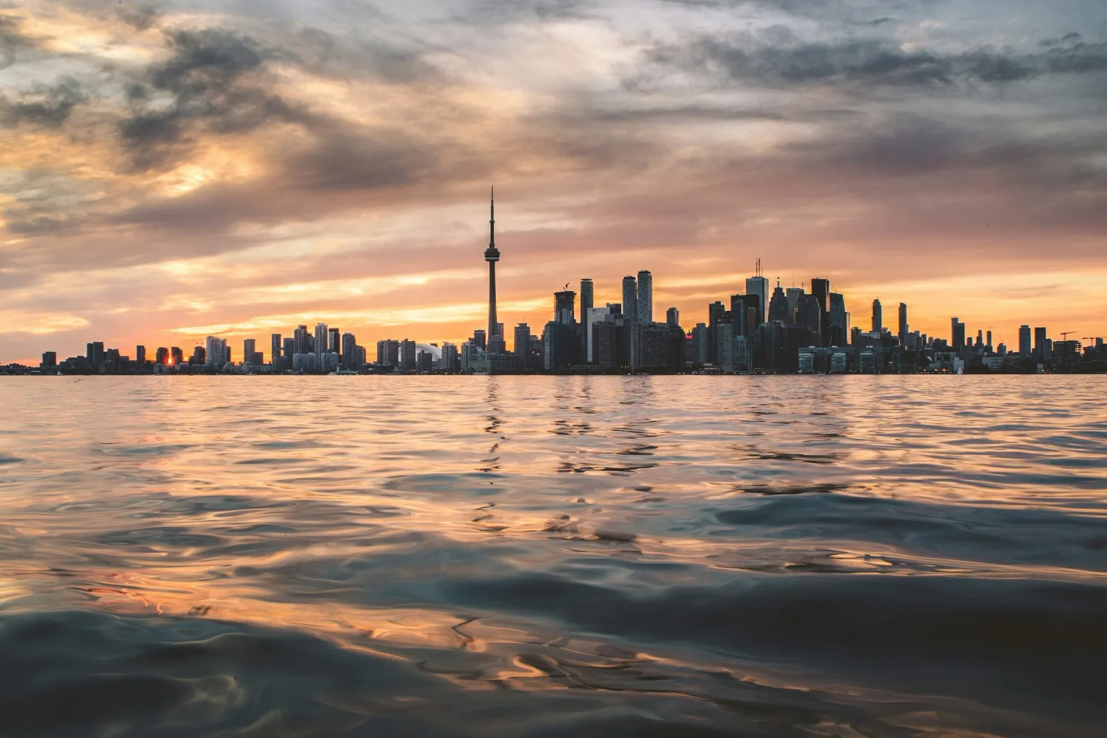 Toronto skyline and waterfront under a cloudy sky.
