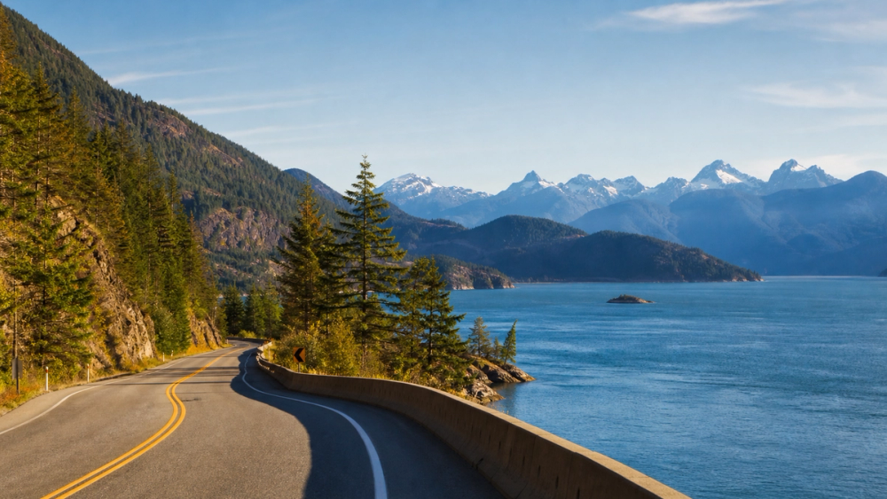 A scenic highway curving beside Howe Sound with coastal mountains on the drive from Vancouver to Whistler