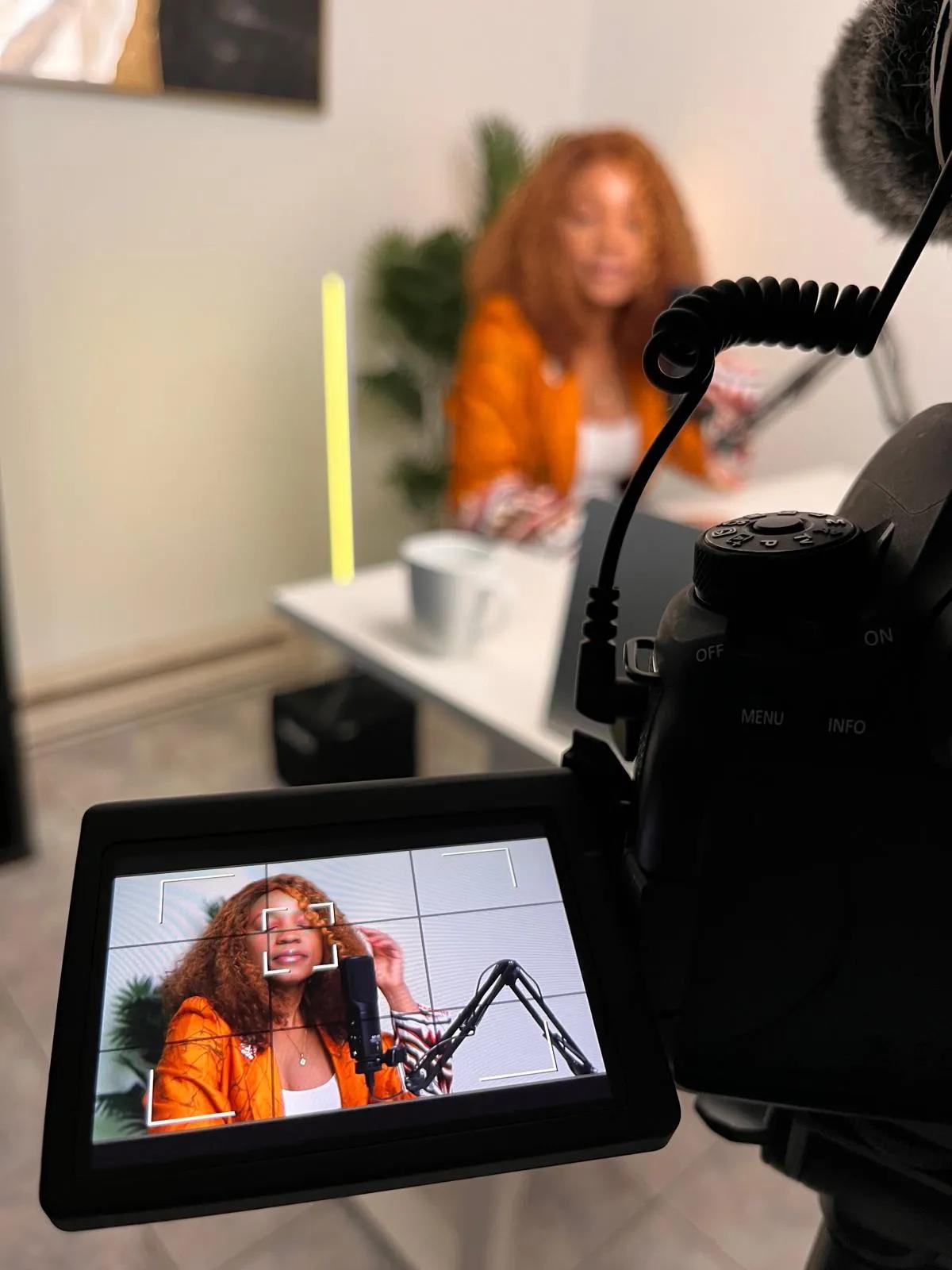 Camera screen framing a podcast host at her microphone