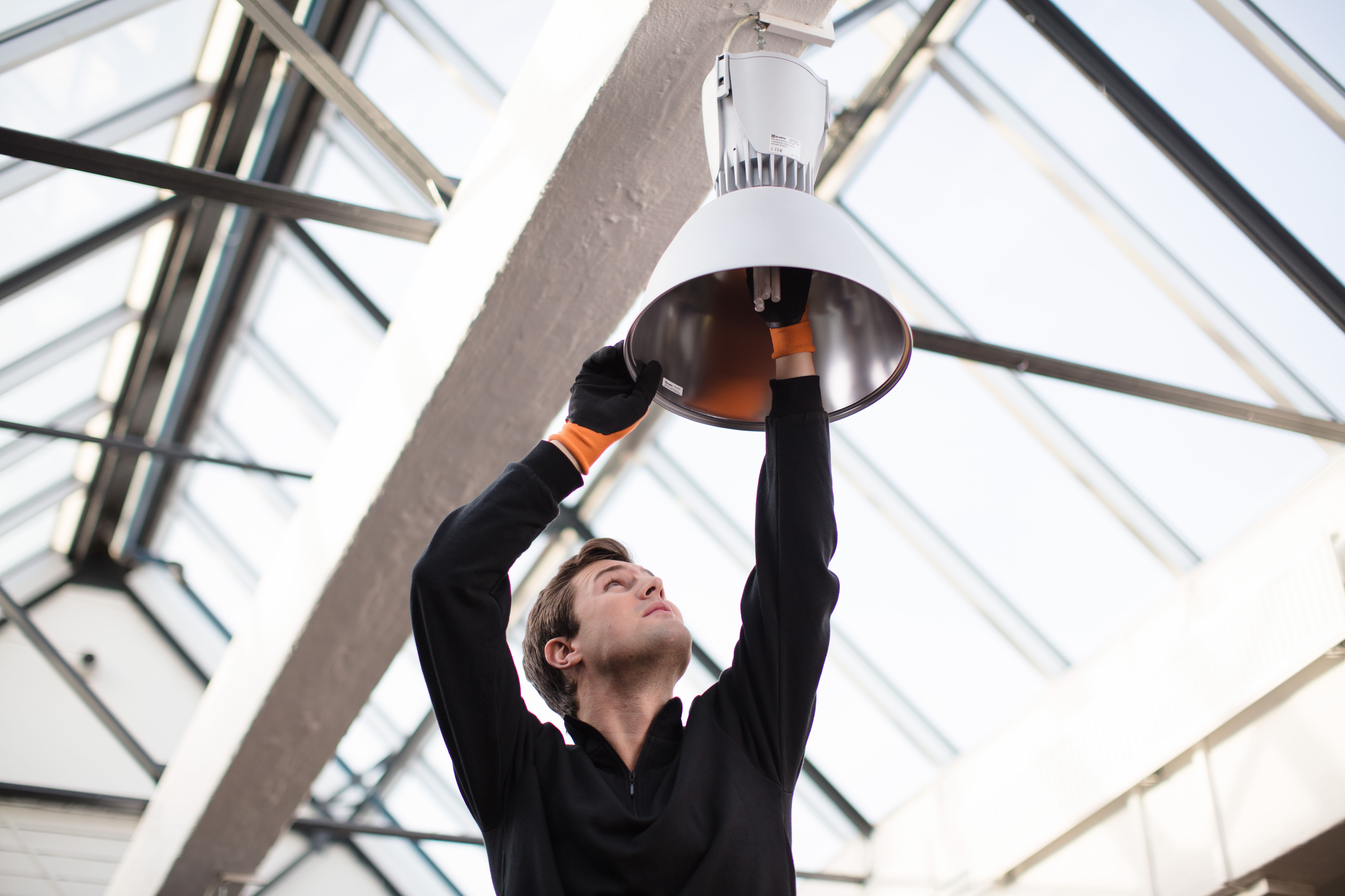 Bilde av mann fra Eir som skifter lyspære i en lampe høyt under taket