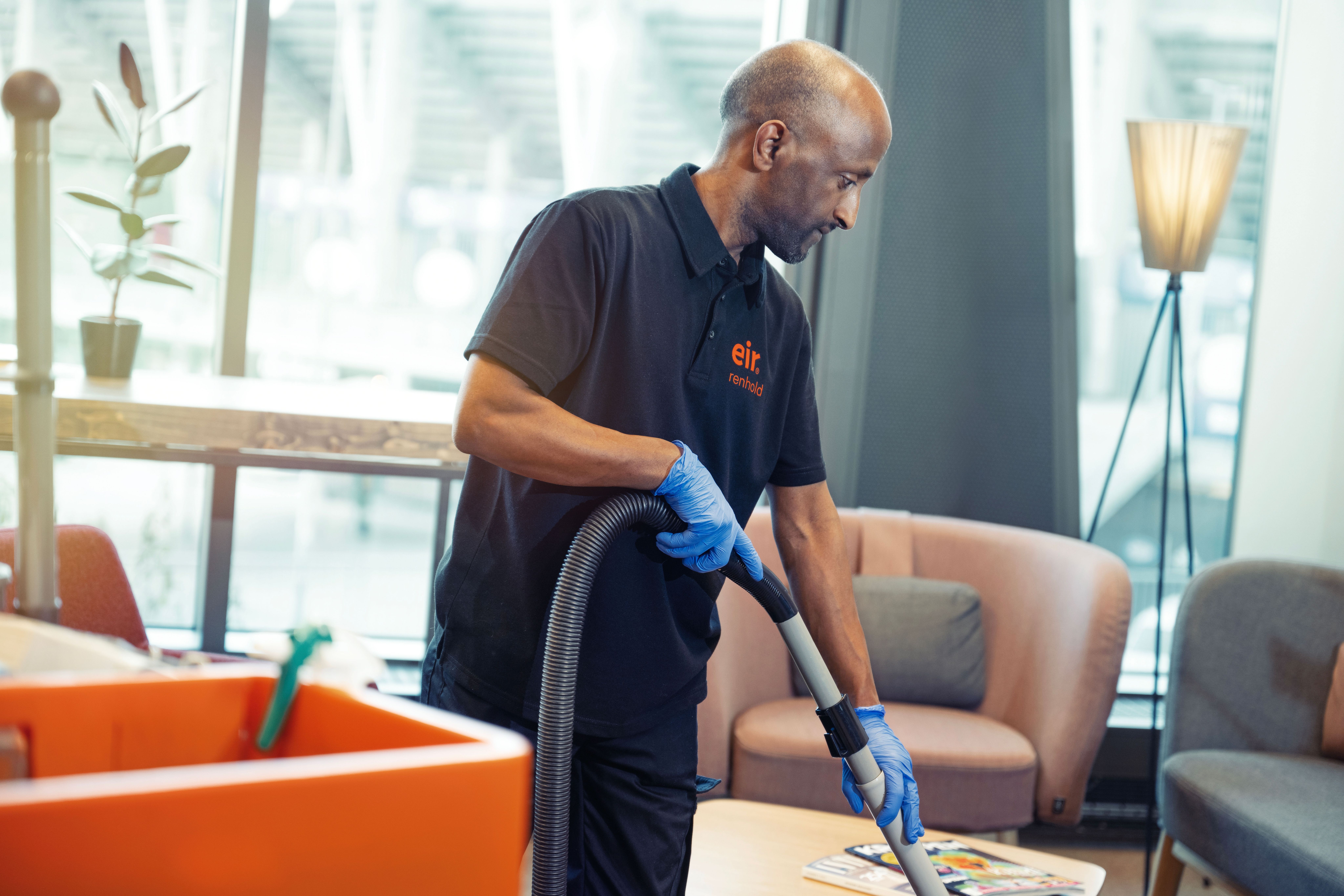 Foto av mann i Eir-uniform fra støvsuger gulv