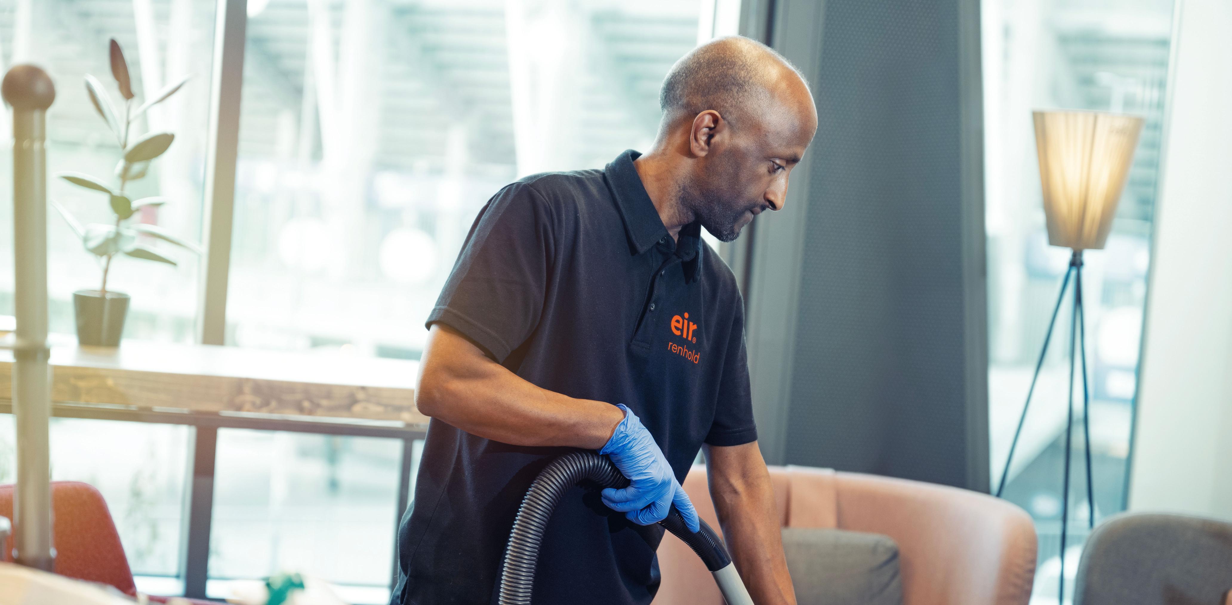 Foto av mann i Eir-uniform fra støvsuger gulv