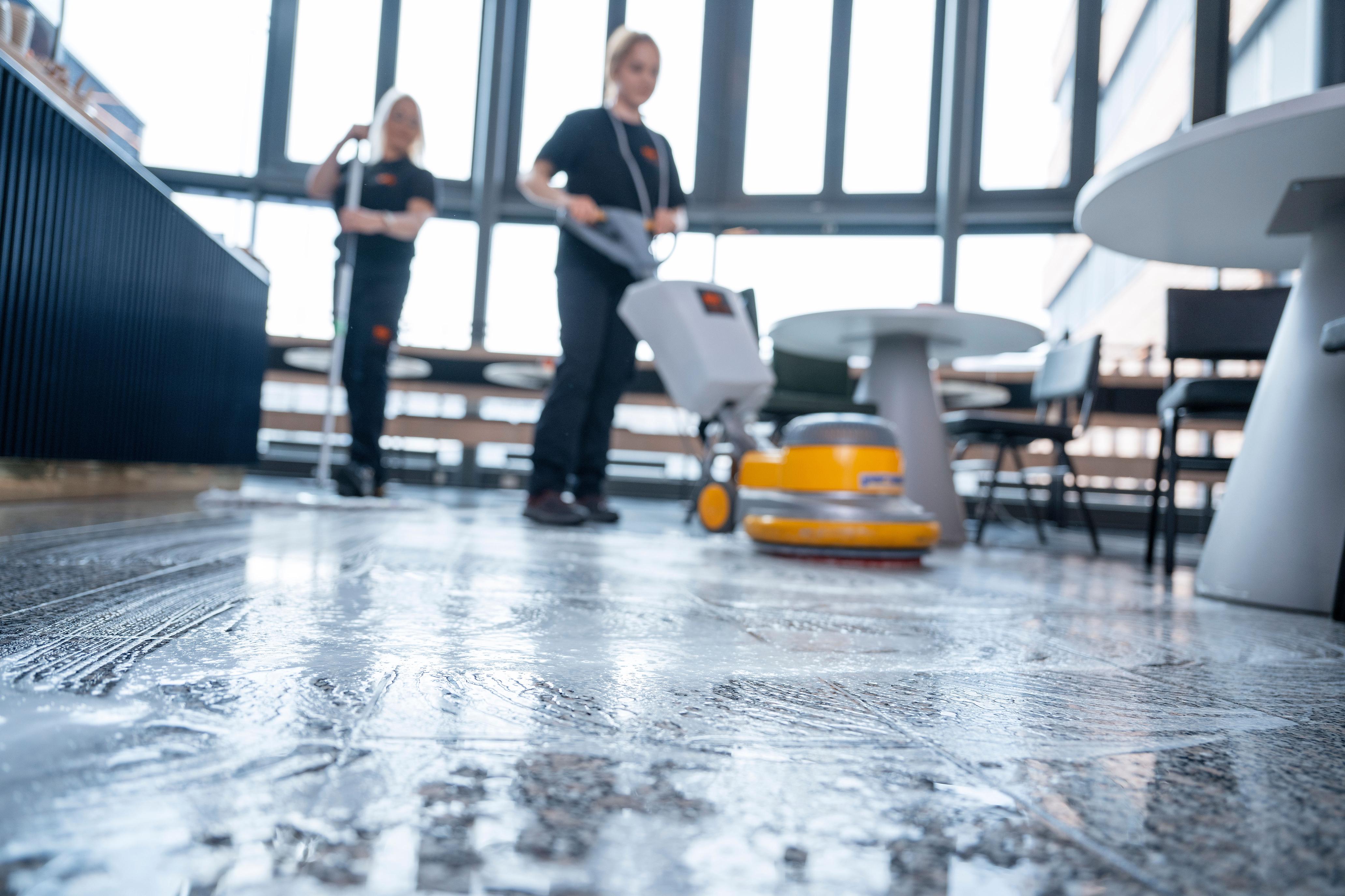 To ansatte fra Eir vasker gulv. En ansatt vasker gulvet med en mopp. En ansatt vasker gulvet med maskin.