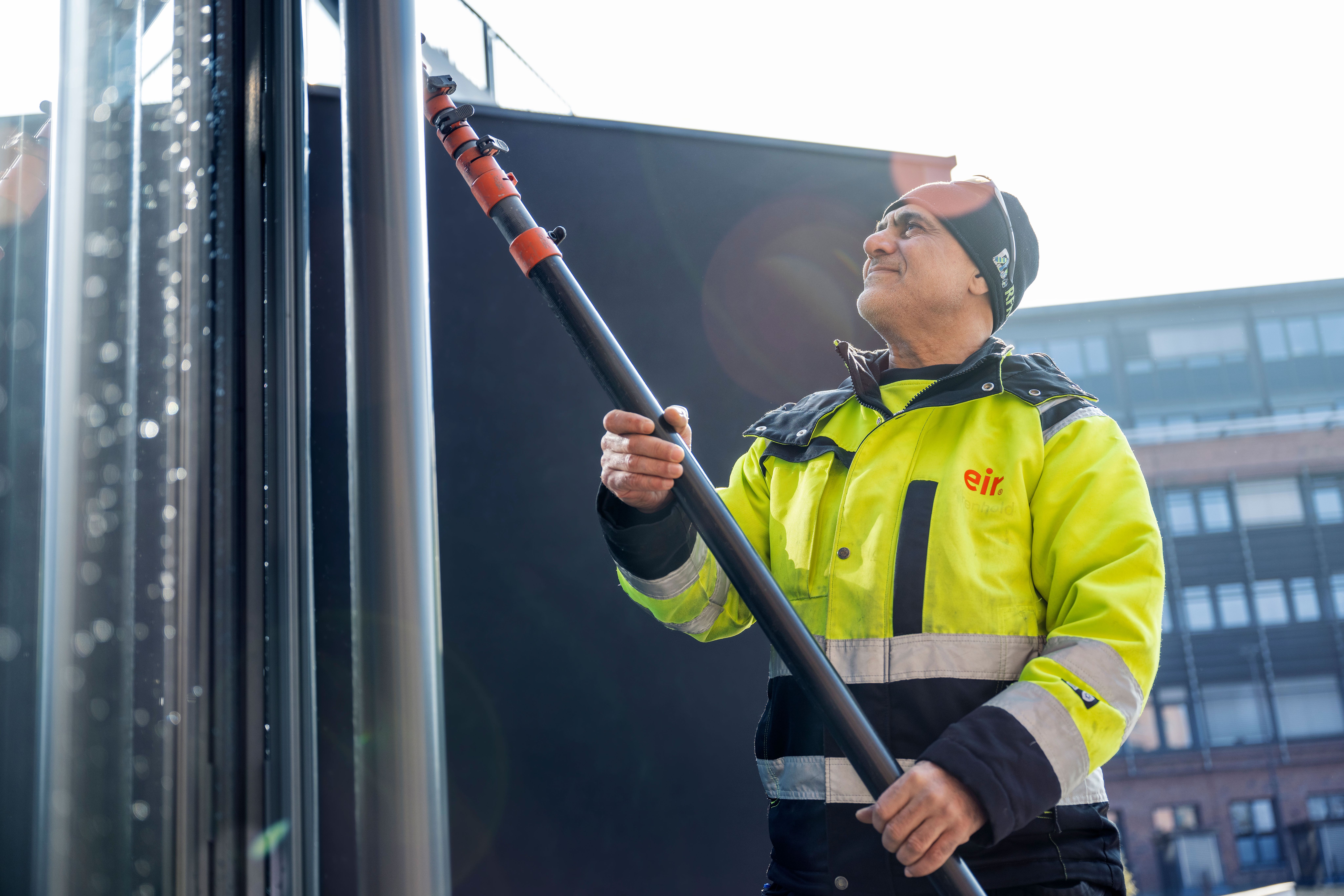 Mann fra Eir vasker vindu utendørs