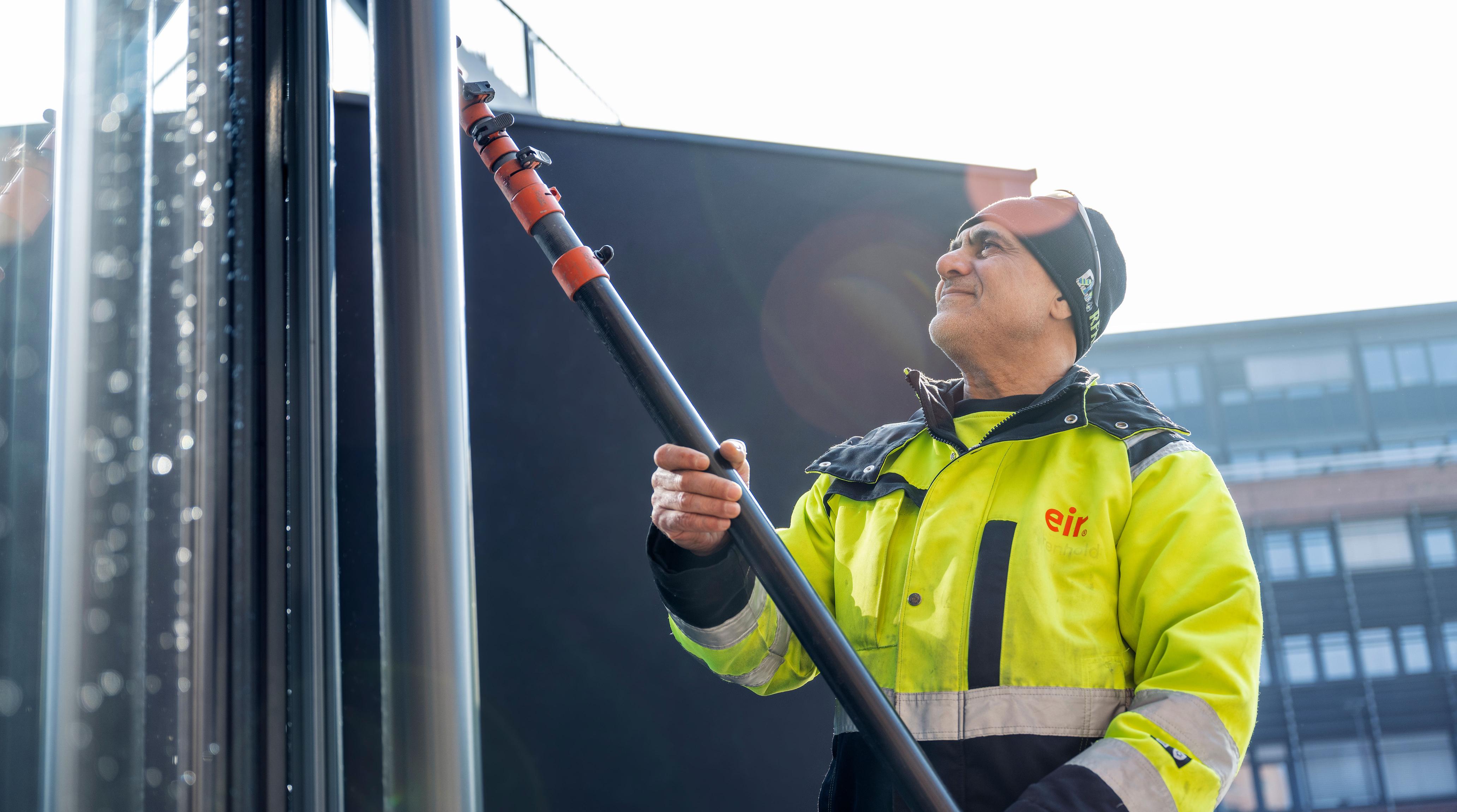 Mann fra Eir vasker vindu utendørs