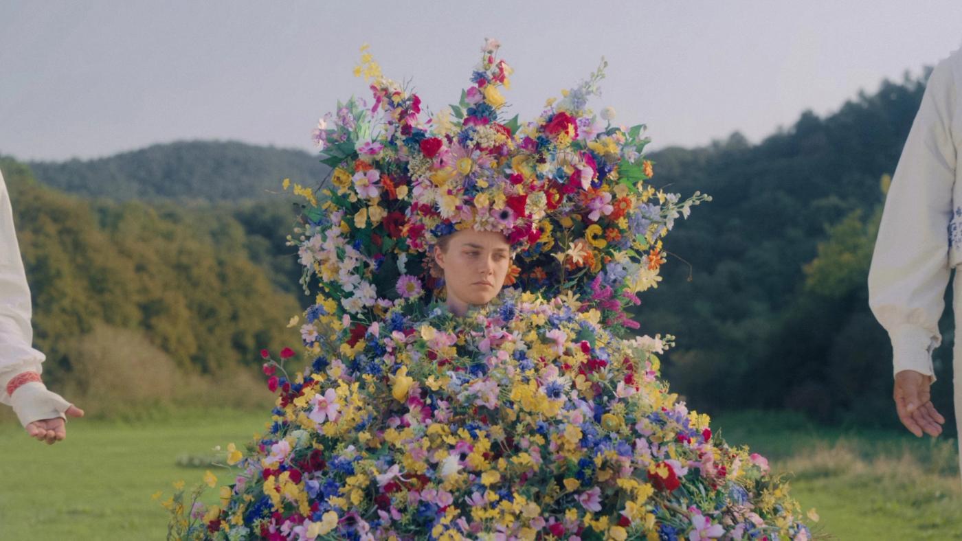Dani berdiri mengenakan gaun bunga penuh sebagai May Queen dalam Midsommar
