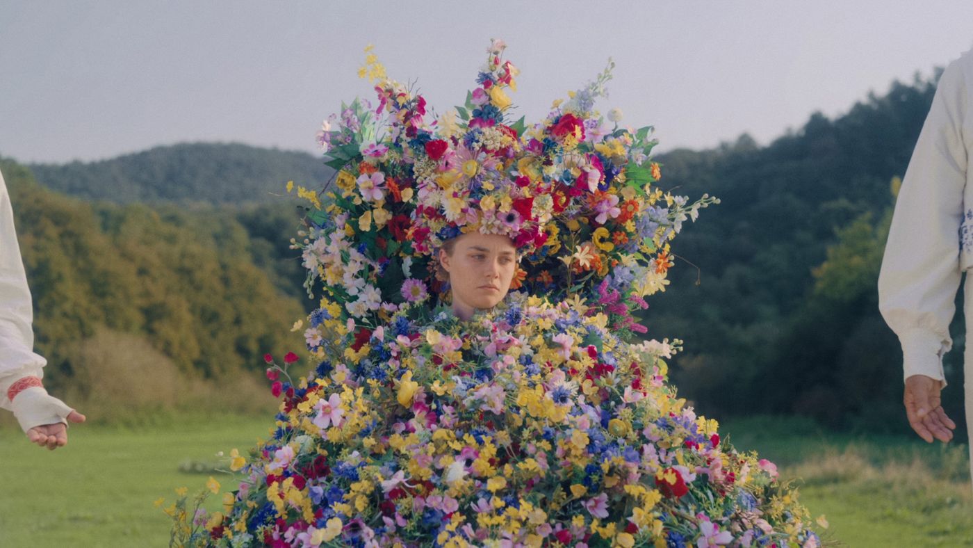 Dani berdiri mengenakan gaun bunga penuh sebagai May Queen dalam Midsommar