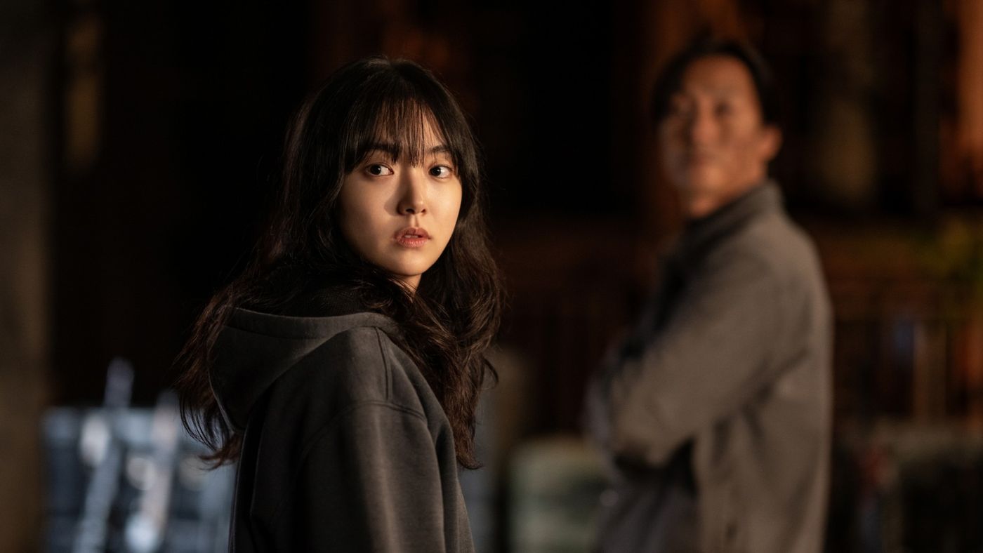 Jeong Ji-an menoleh dengan ekspresi curiga sementara Jeong Jin-man berdiri di belakangnya
