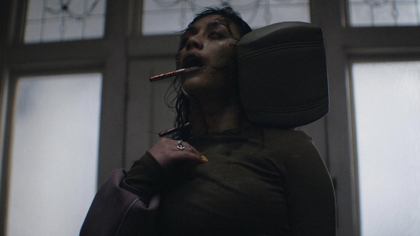 Still resmi Evil Dead Burn menampilkan momen Alice memegang Belati Kandarian di tengah api
