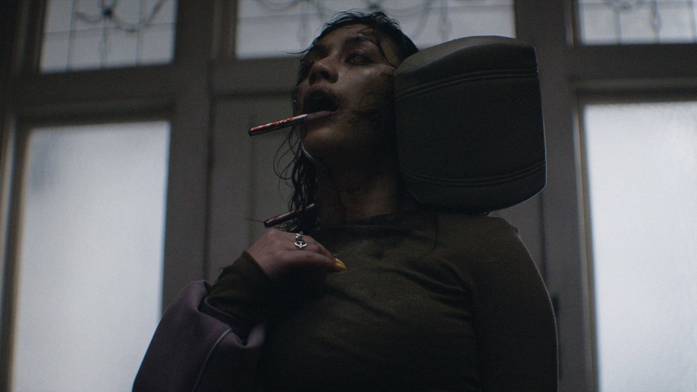 Still resmi Evil Dead Burn menampilkan momen Alice memegang Belati Kandarian di tengah api