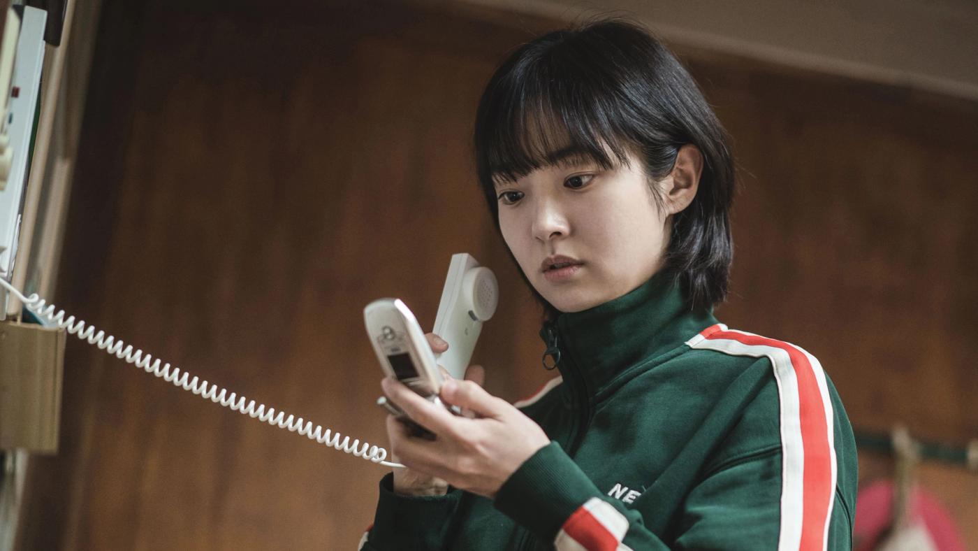 Jeong Ji-an memegang telepon rumah dengan ekspresi serius dalam A Shop for Killers