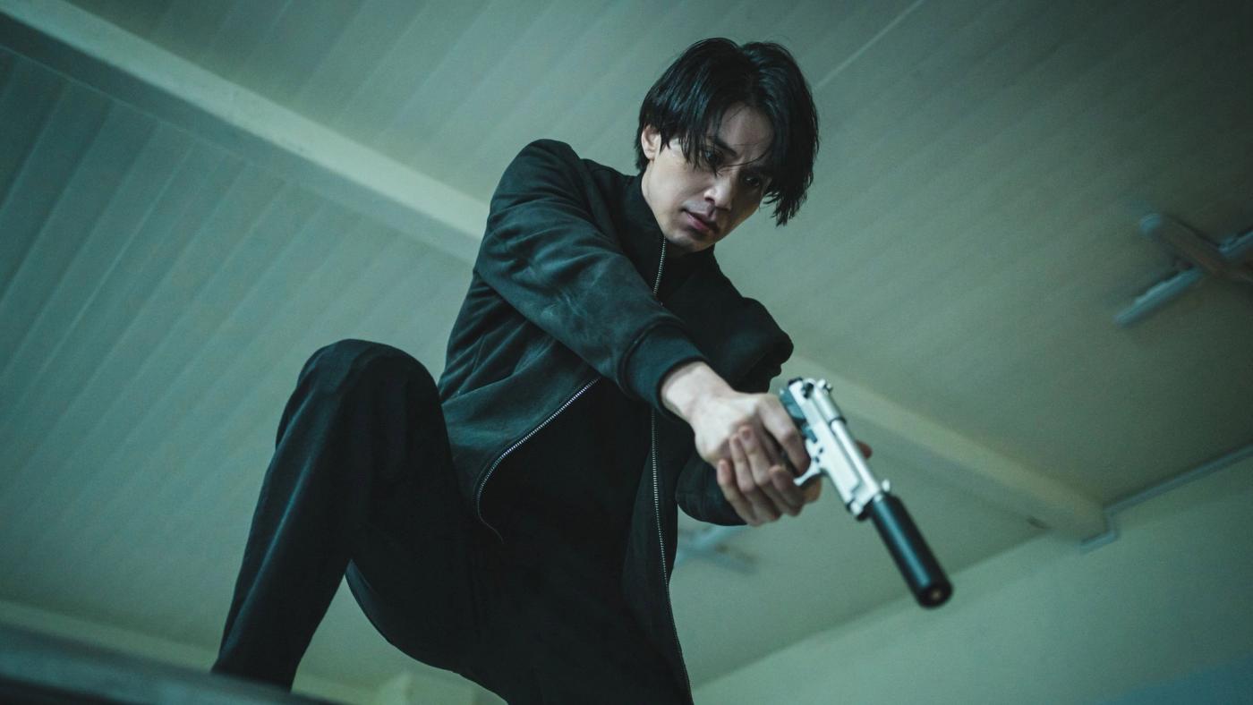 Jeong Jin-man membidik pistol dengan sudut pengambilan rendah dalam A Shop for Killers