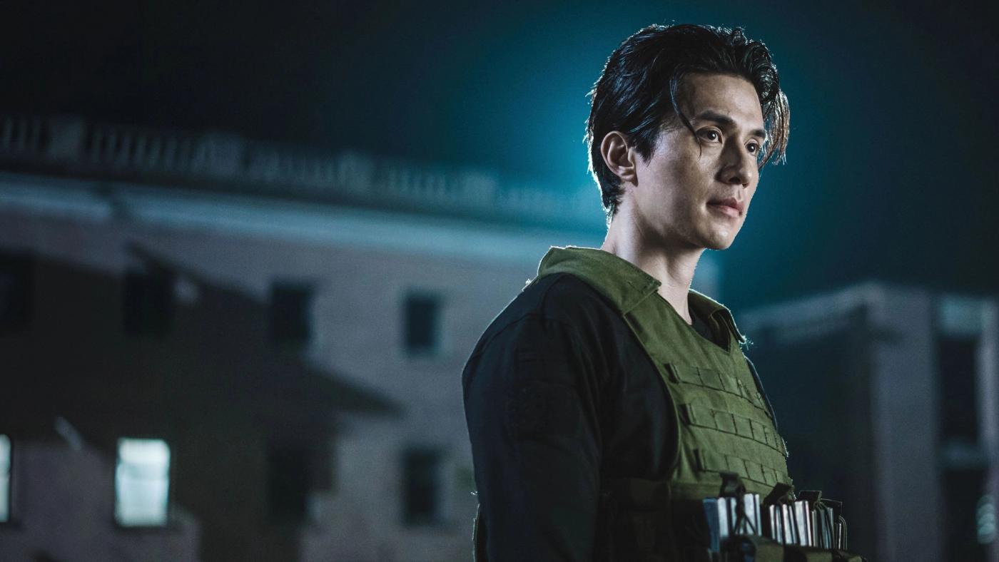 Jeong Jin-man mengenakan rompi taktis di tengah malam dalam A Shop for Killers Season 2