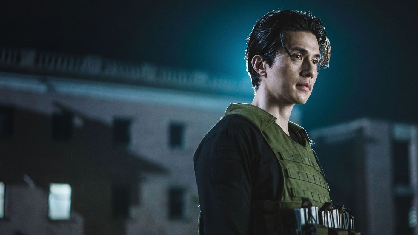 Jeong Jin-man mengenakan rompi taktis di tengah malam dalam A Shop for Killers Season 2