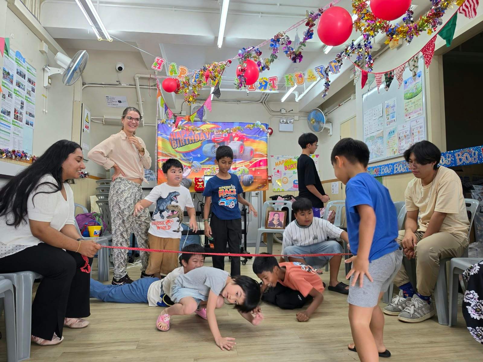 Children laugh and duck beneath the limbo rope.