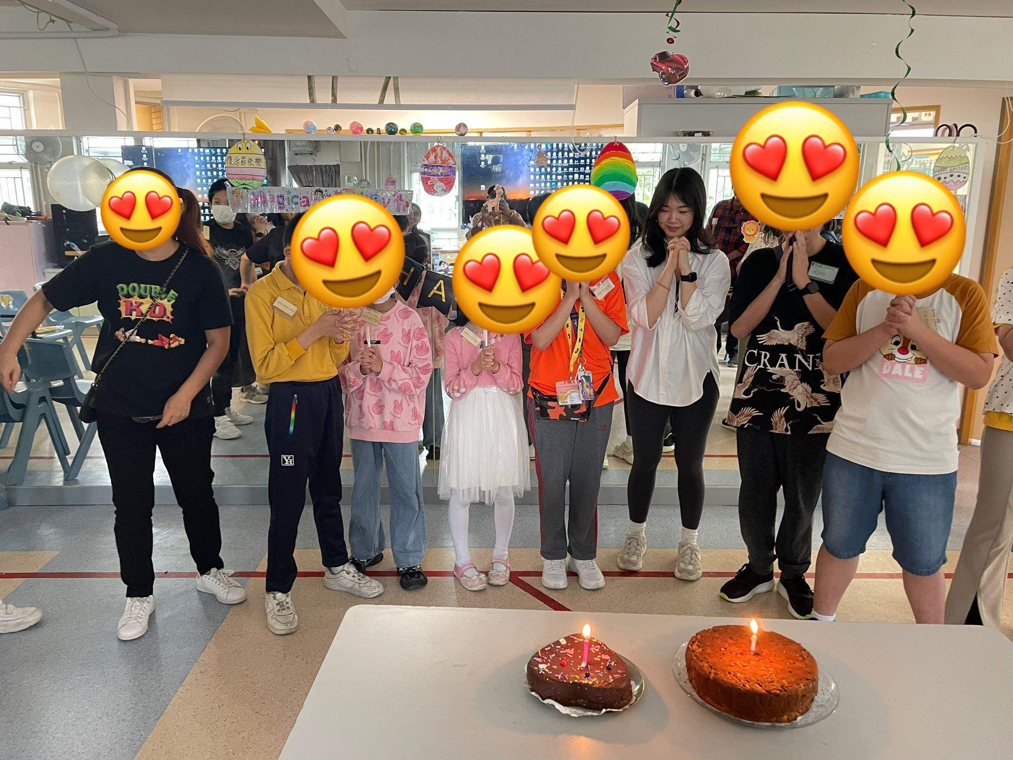 A group poses behind two cakes with glowing candles.