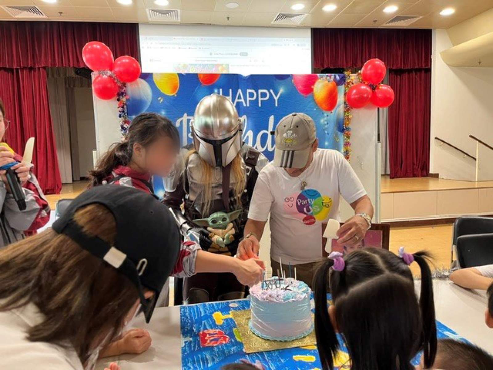 Adults prepare candles on a birthday cake at a table.