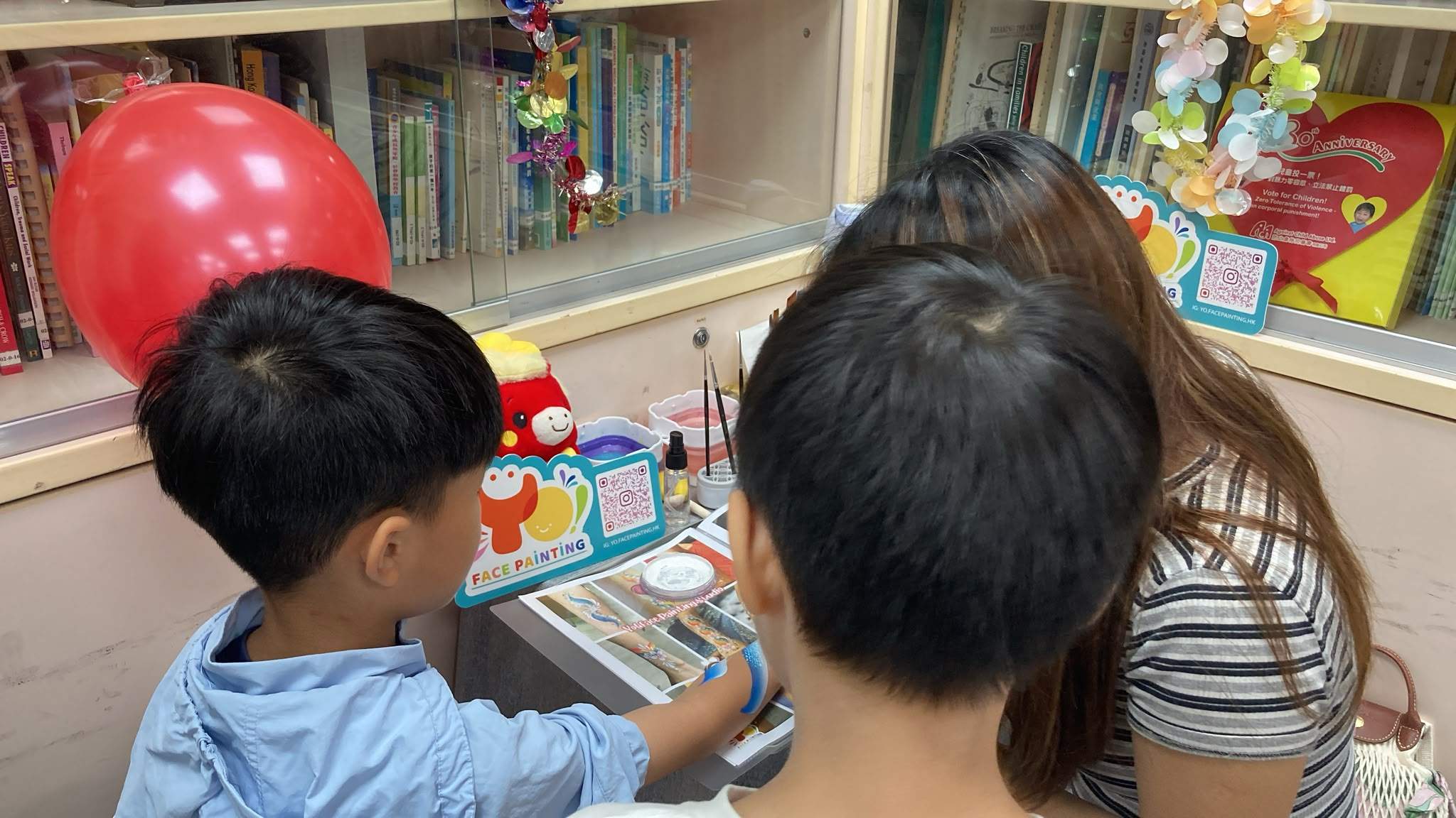 Children choose designs at a face-painting table.