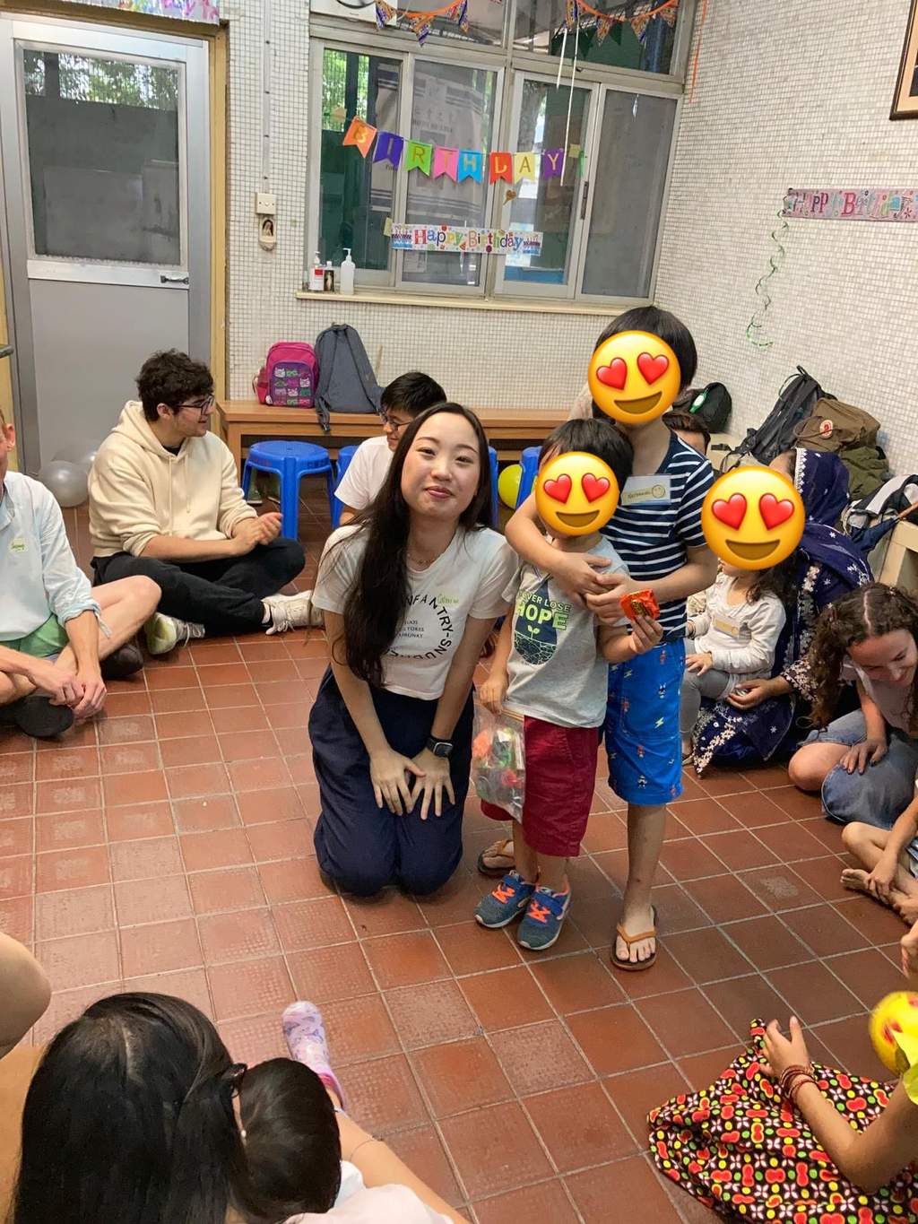 An adult kneels beside a child during a group activity.