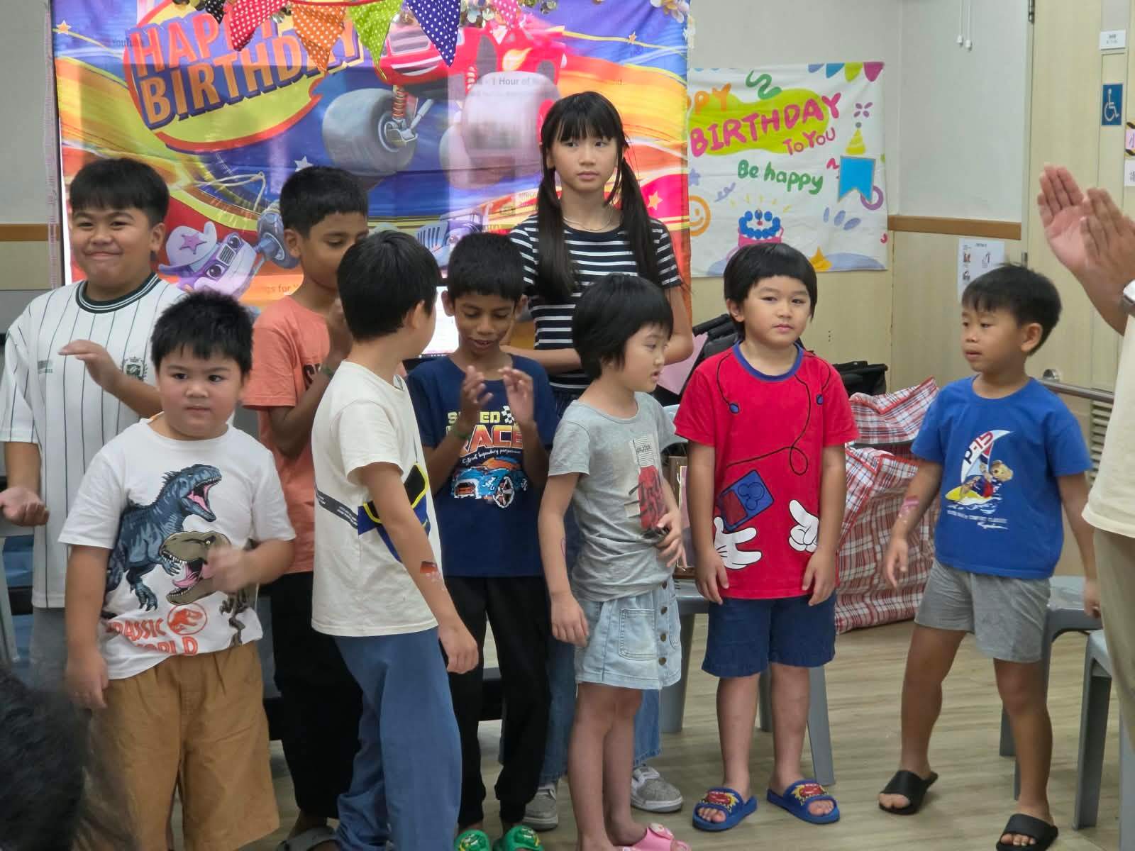 Children gather together in front of the birthday backdrop.
