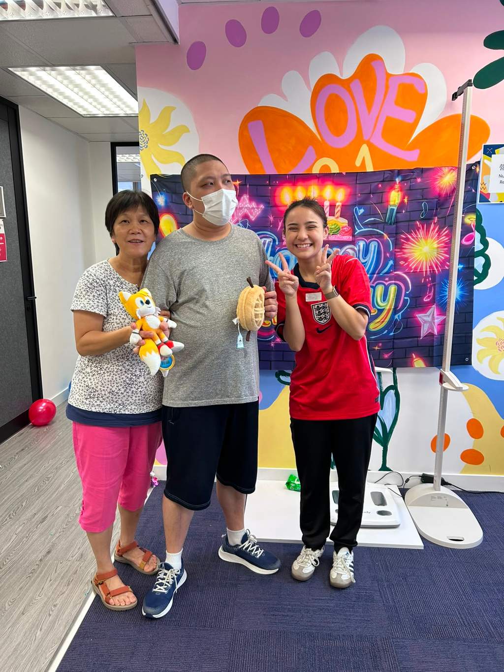 Three people stand together while holding several small toys.