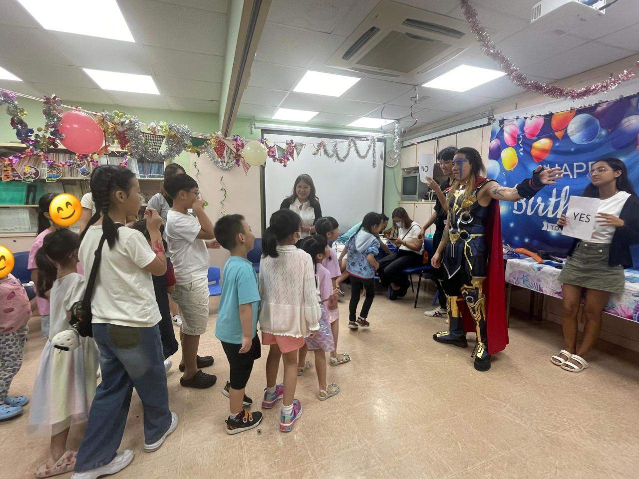Children queue beside a costumed performer in the decorated room.