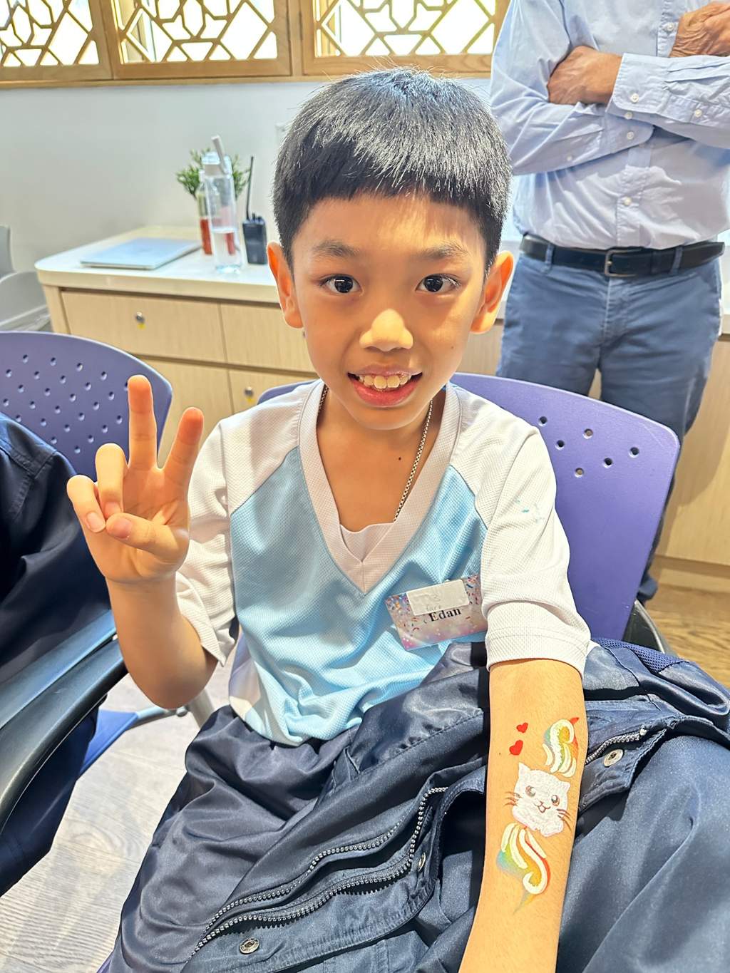 A seated child displays painted artwork on their forearm.