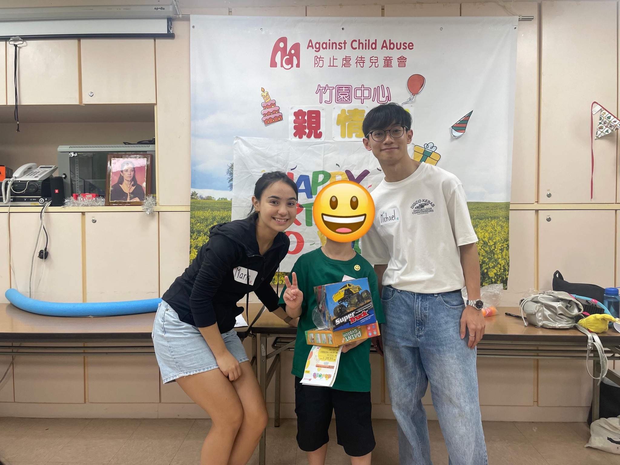 Two adults pose with a child holding a colourful gift.