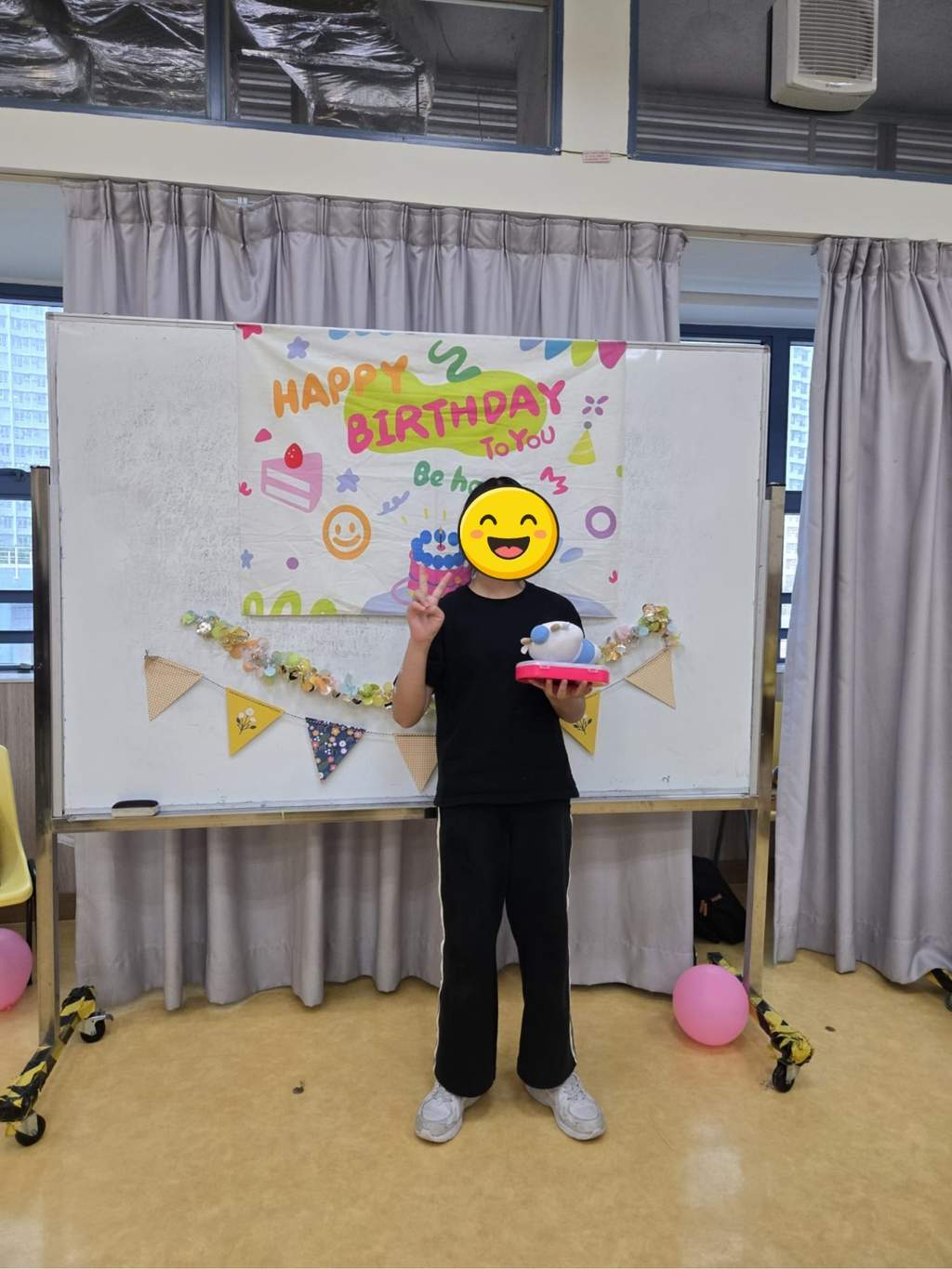 A participant displays a toy and gift before the birthday backdrop.