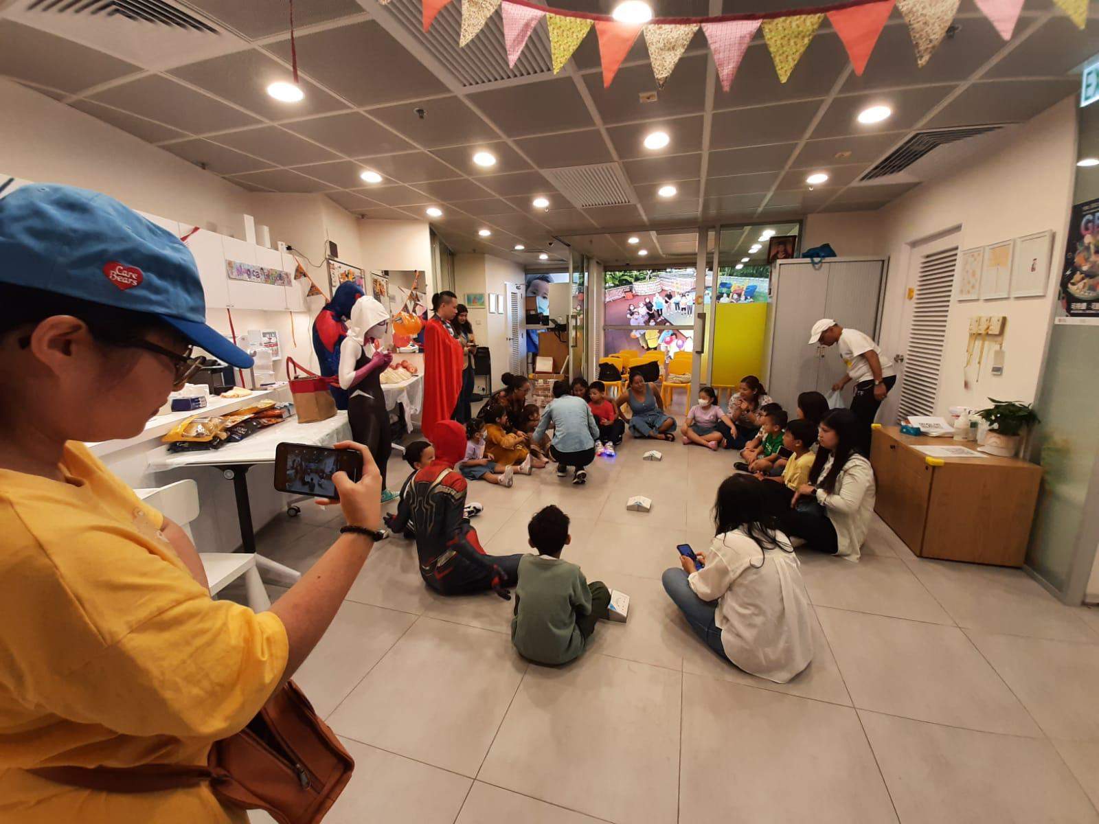 A seated group watches costumed performers lead an activity.