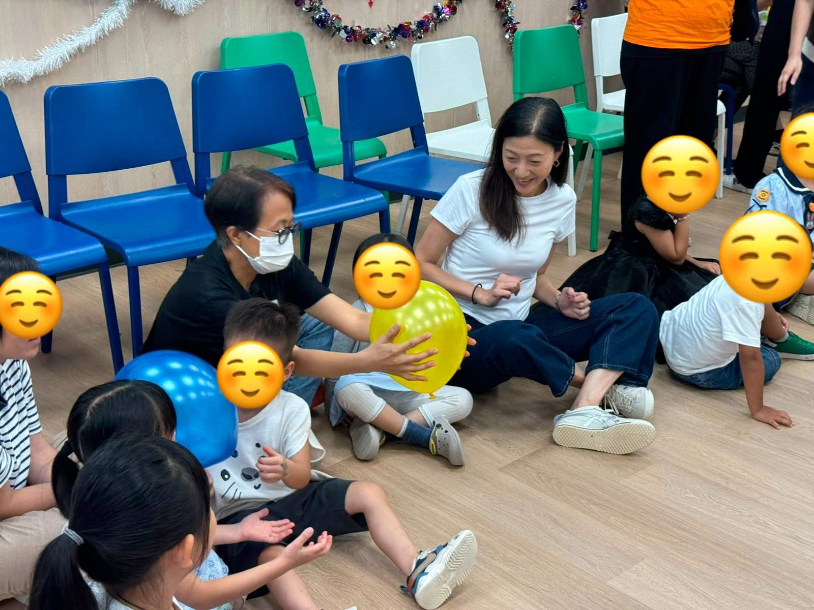 Children and adults play together with colourful balloons.