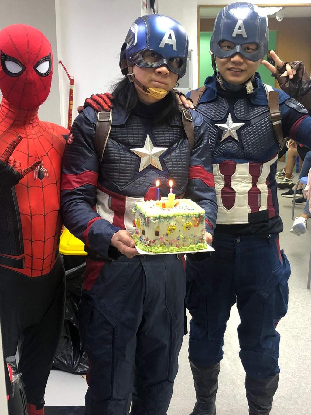 Costumed performers pose together holding a decorated cake.