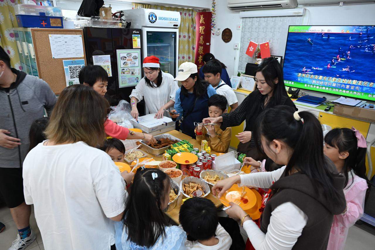 Children and adults gather around a table filled with food.