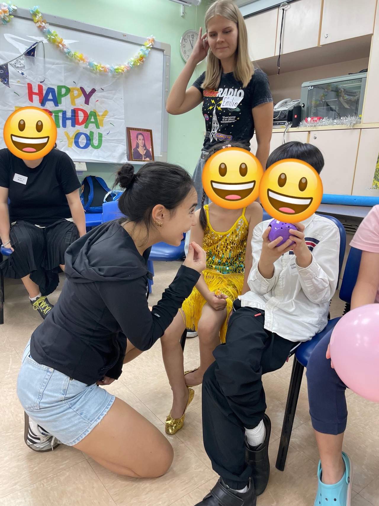 Adults help children during a balloon activity in the room.
