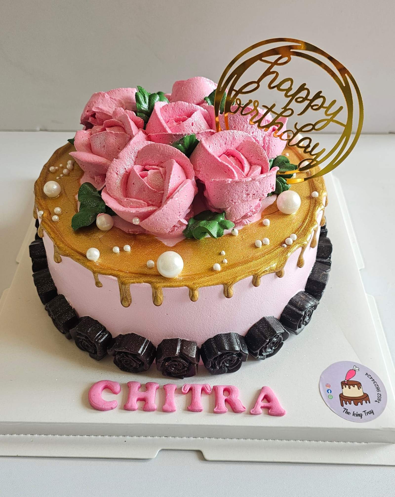 Pink and gold floral birthday cake topped with pink roses, pearl decorations and a gold birthday topper.