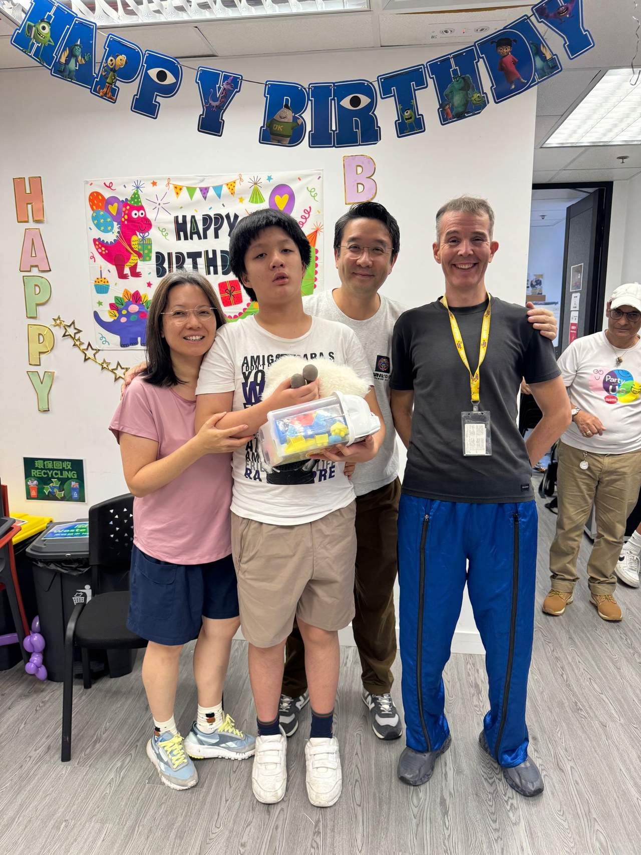 Four people pose together while displaying a boxed gift.