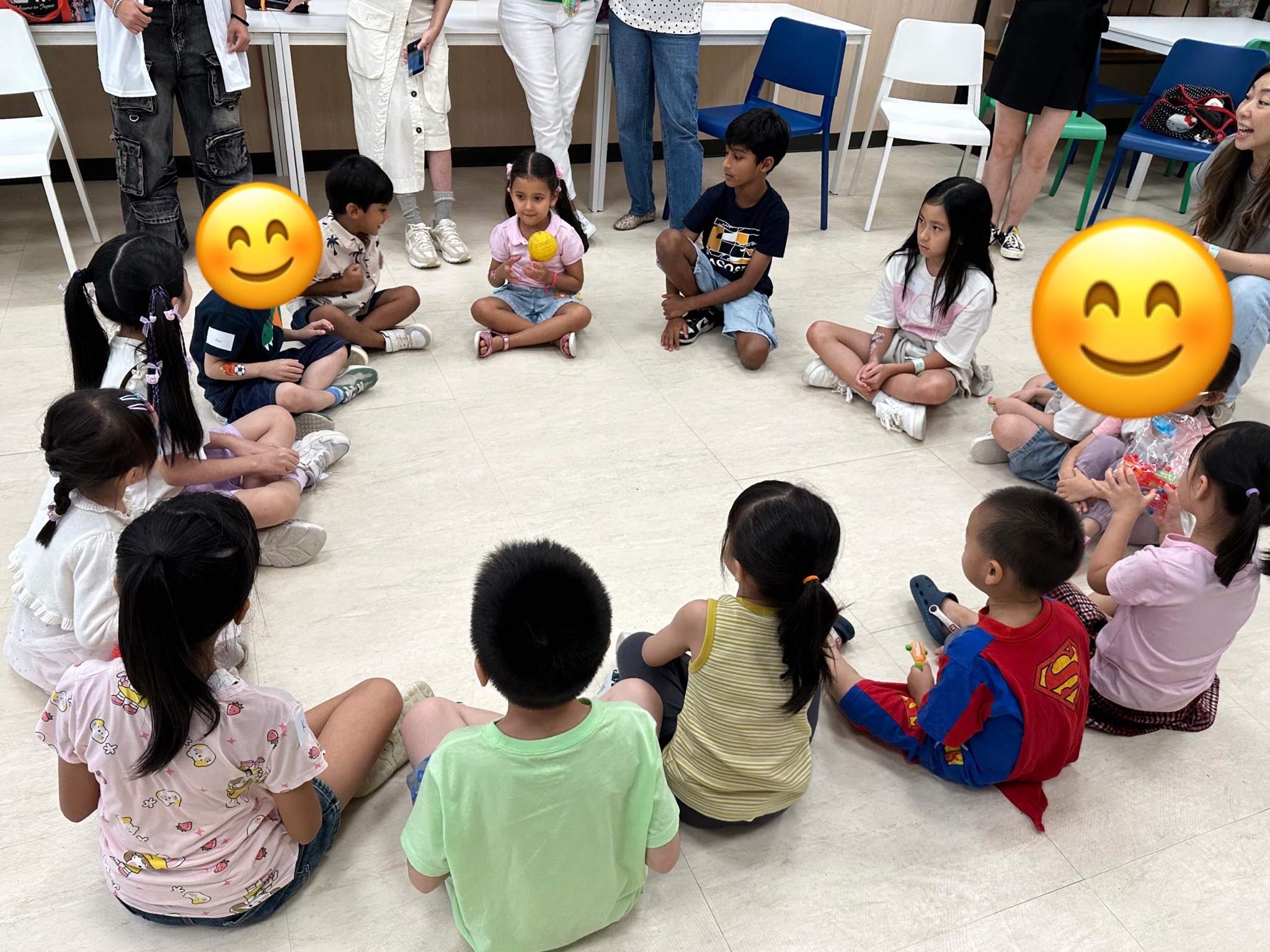 Children sit in a wide floor circle during an activity.