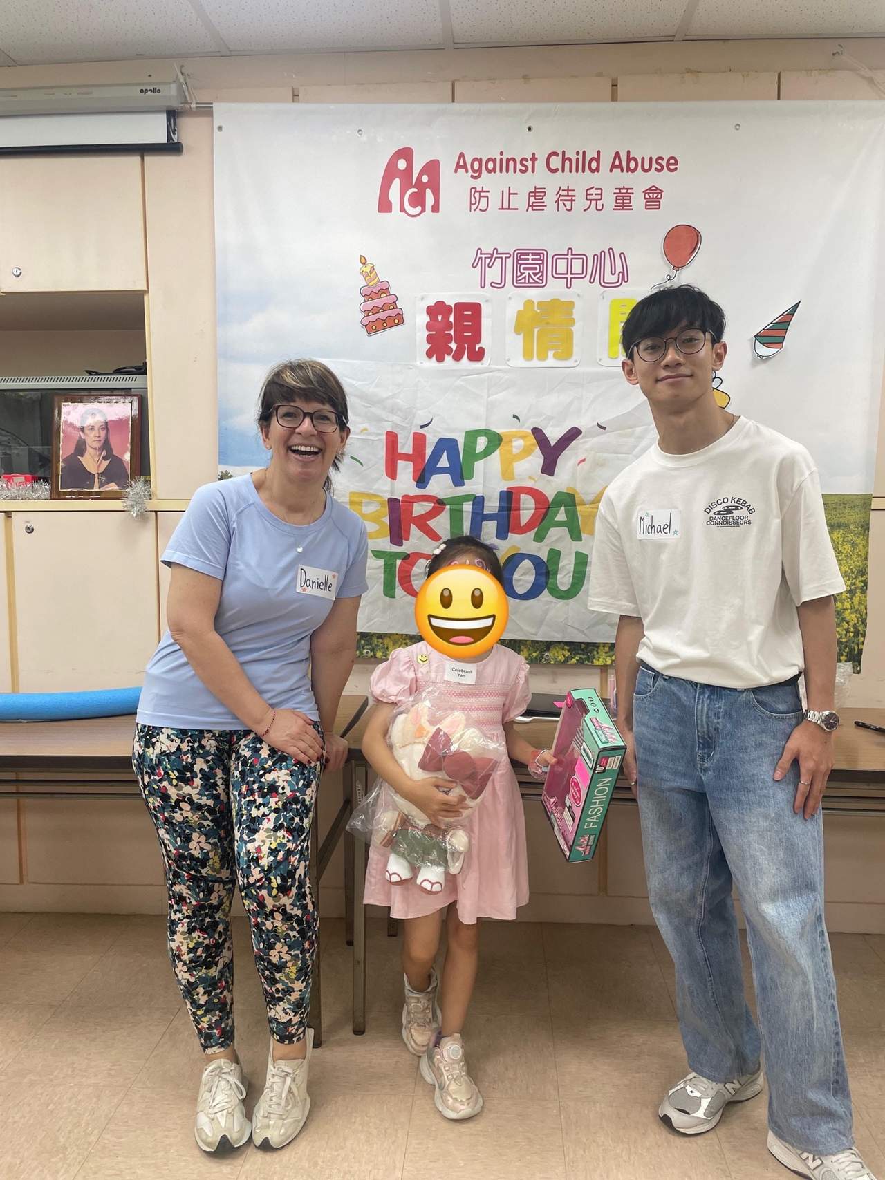 Two adults pose with a child holding a gift bag.