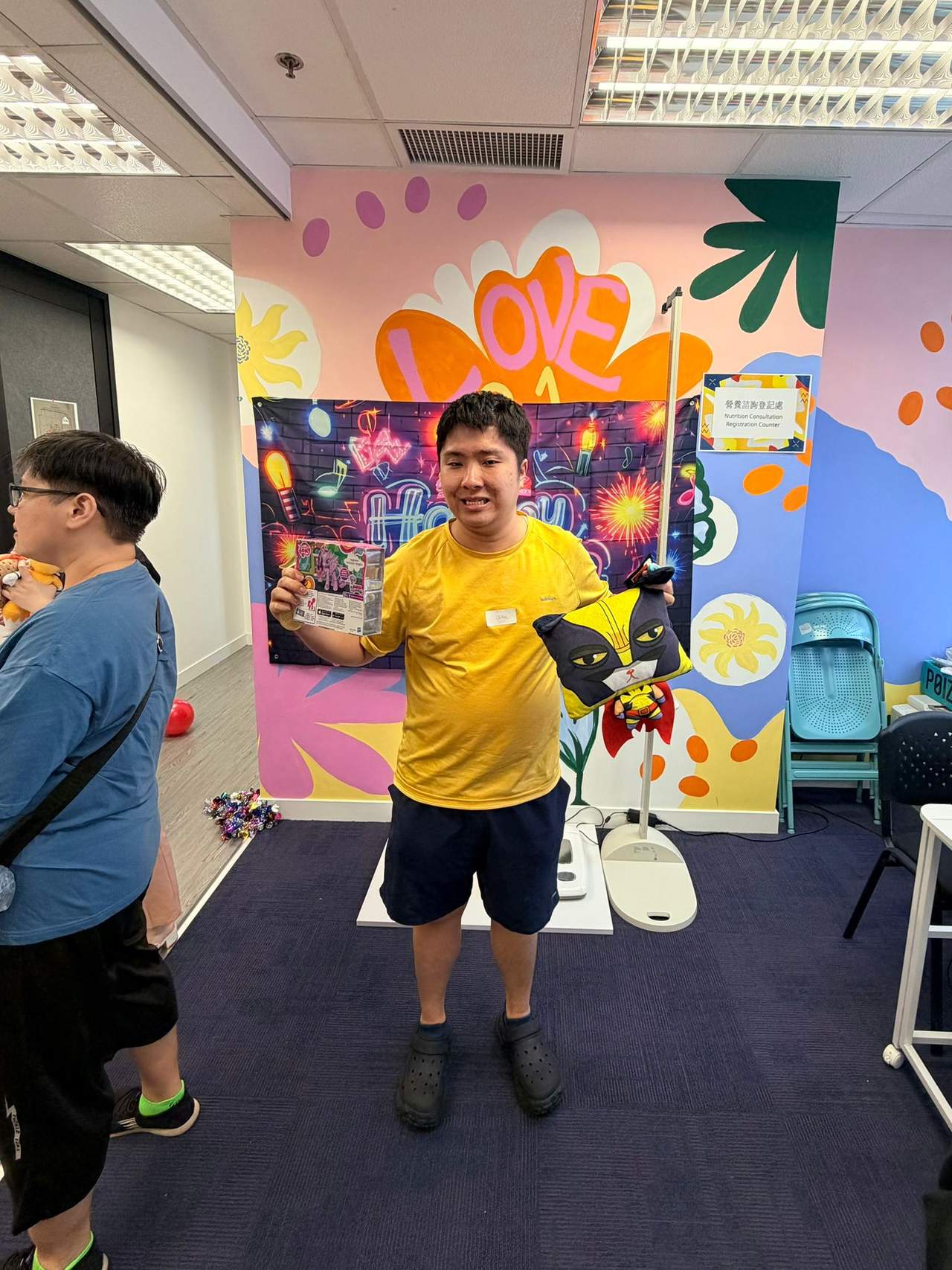 A person stands holding a small gift beside the backdrop.