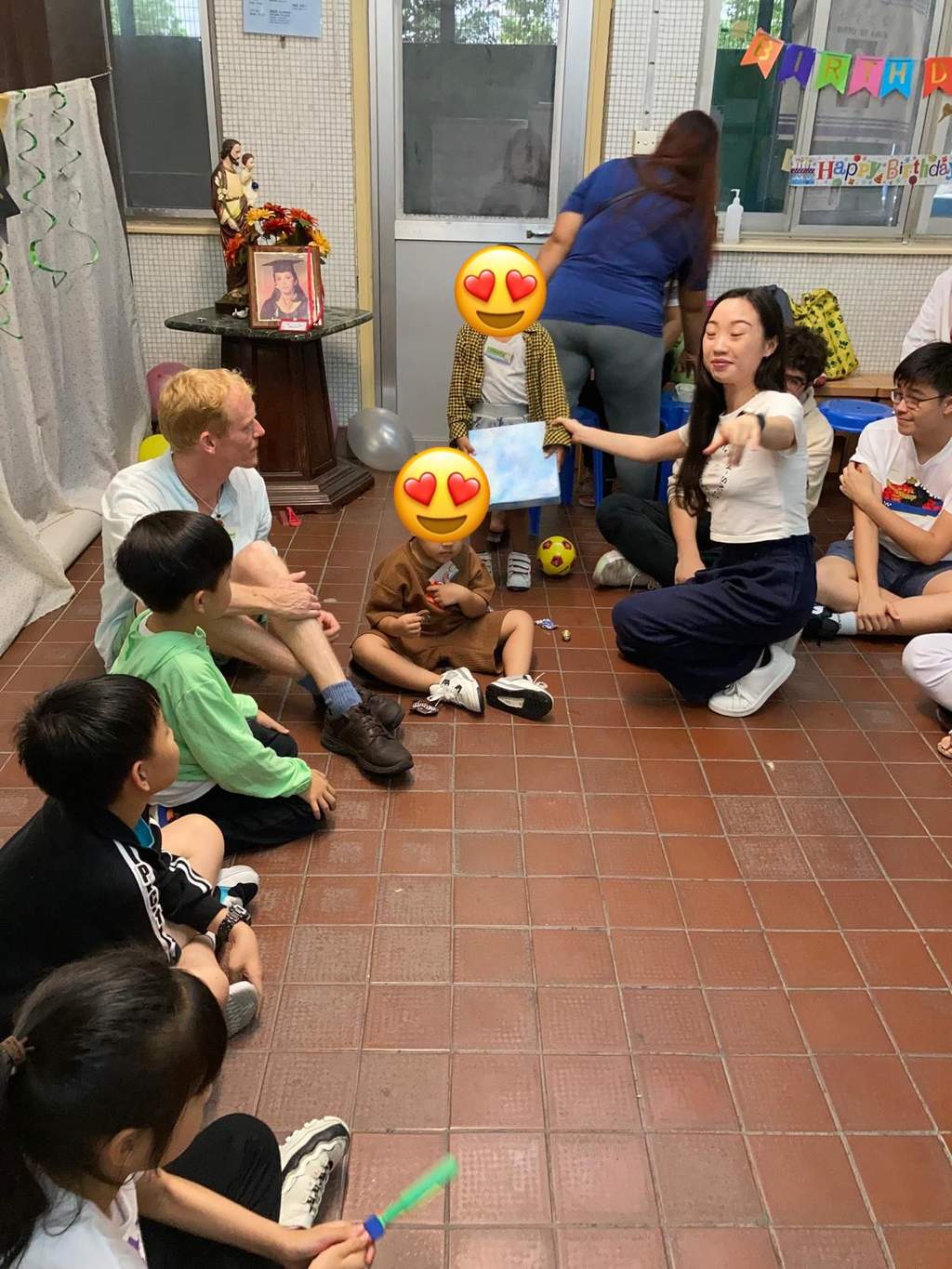 Children and adults sit in a wide circle on the floor.