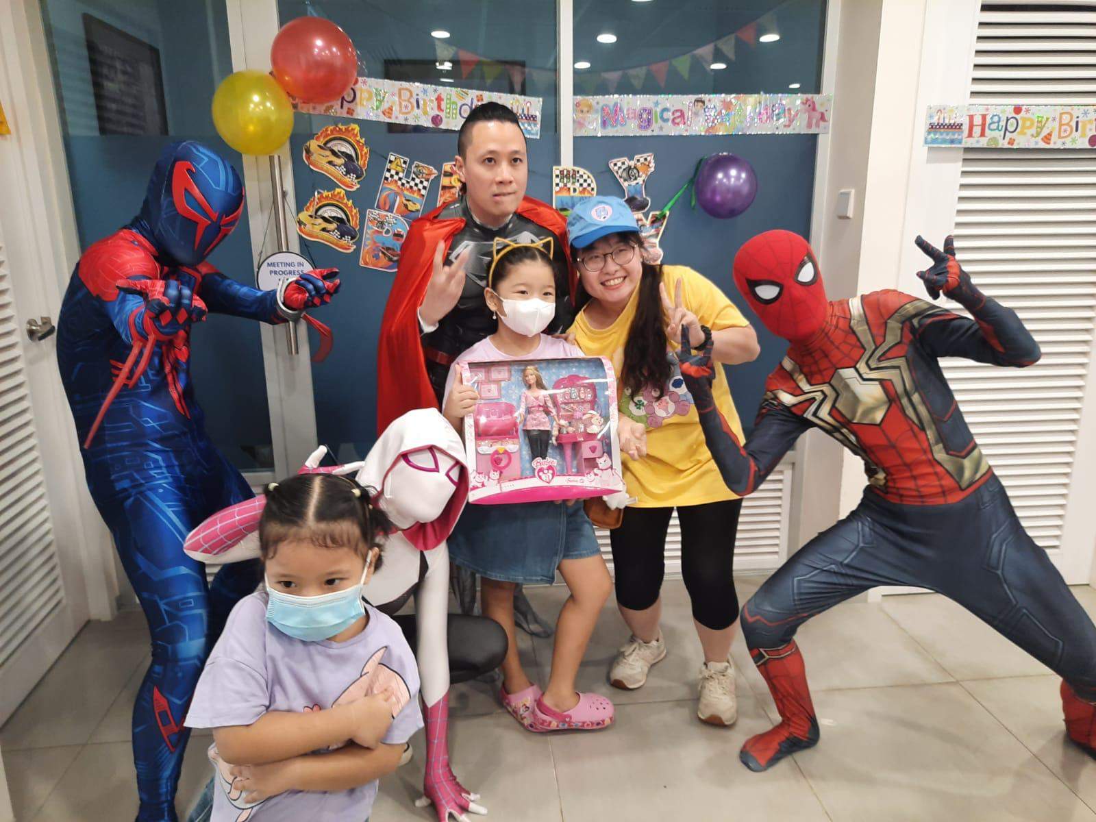 Costumed performers and adults pose with children holding gifts.