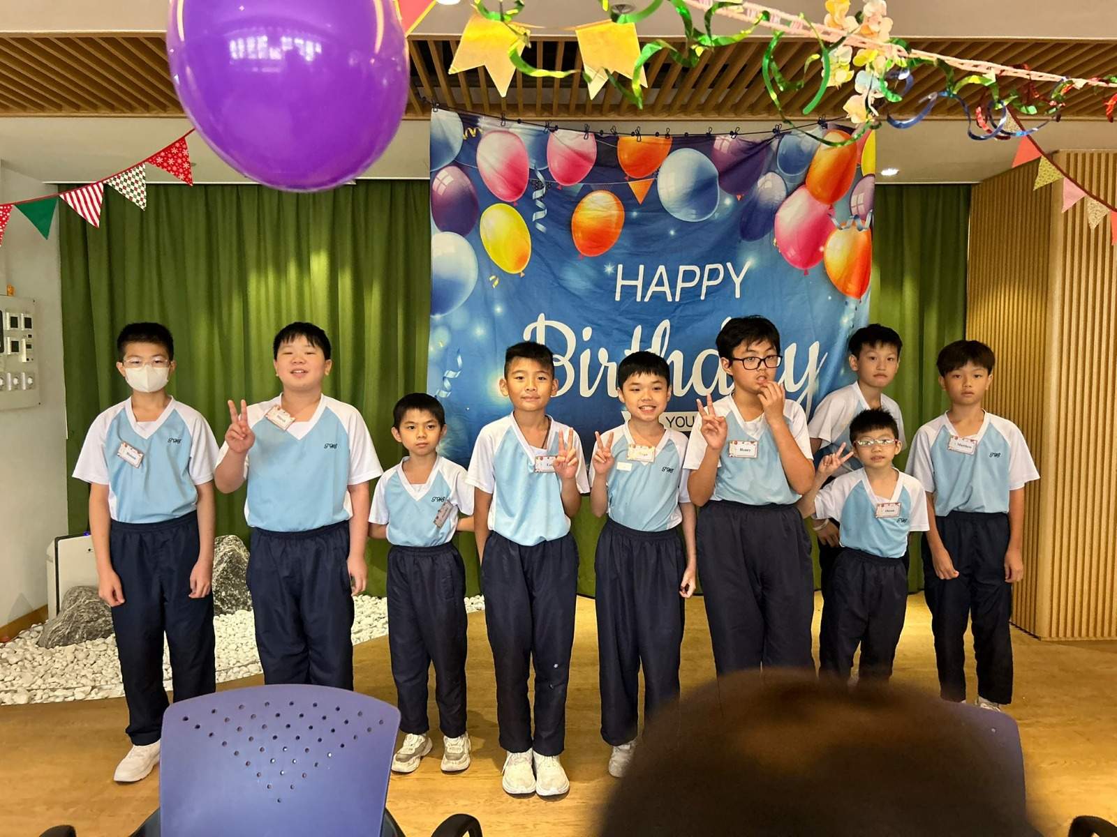 A row of children poses in front of the birthday backdrop.
