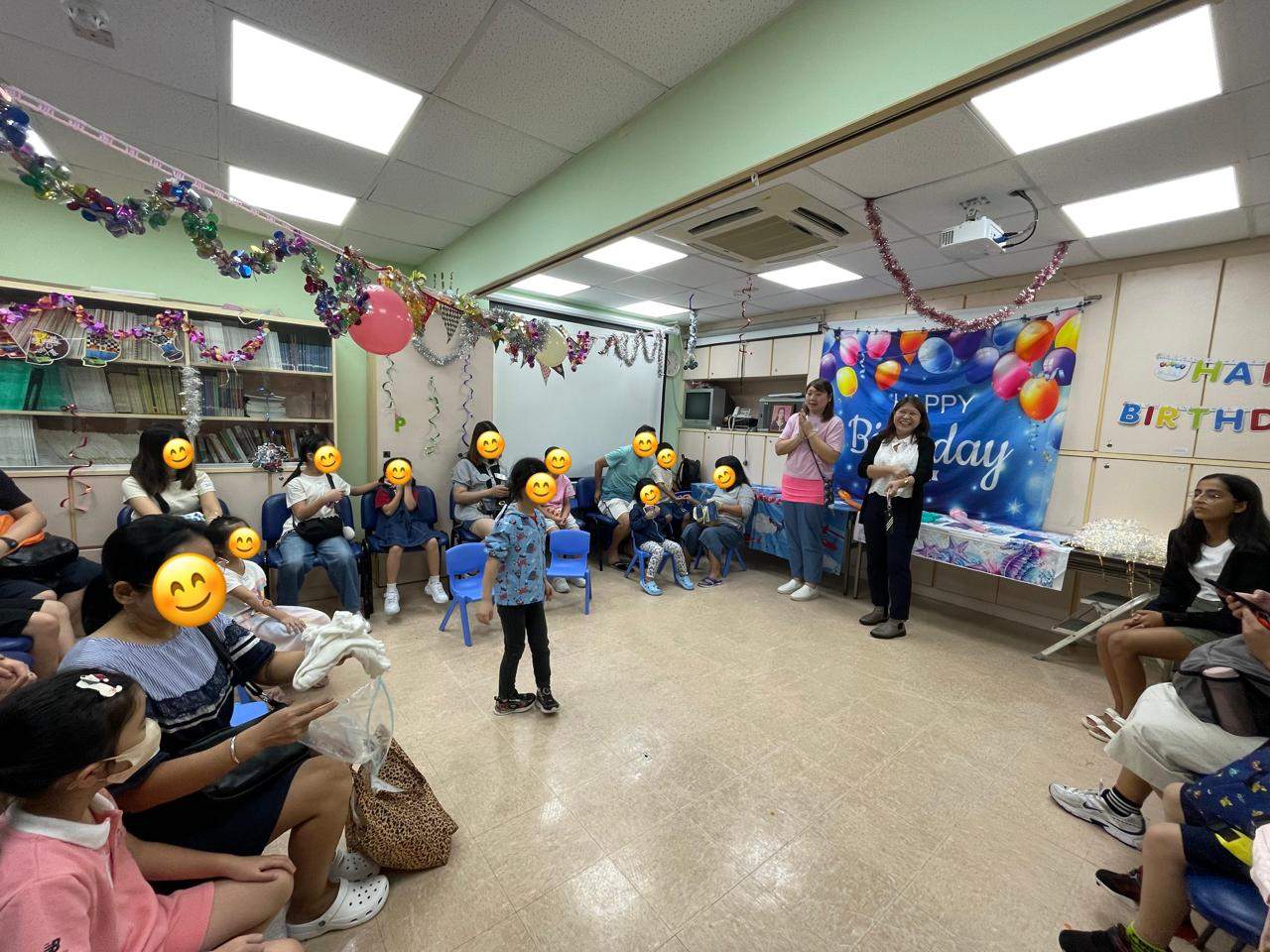 A child performs before an audience seated around the room.