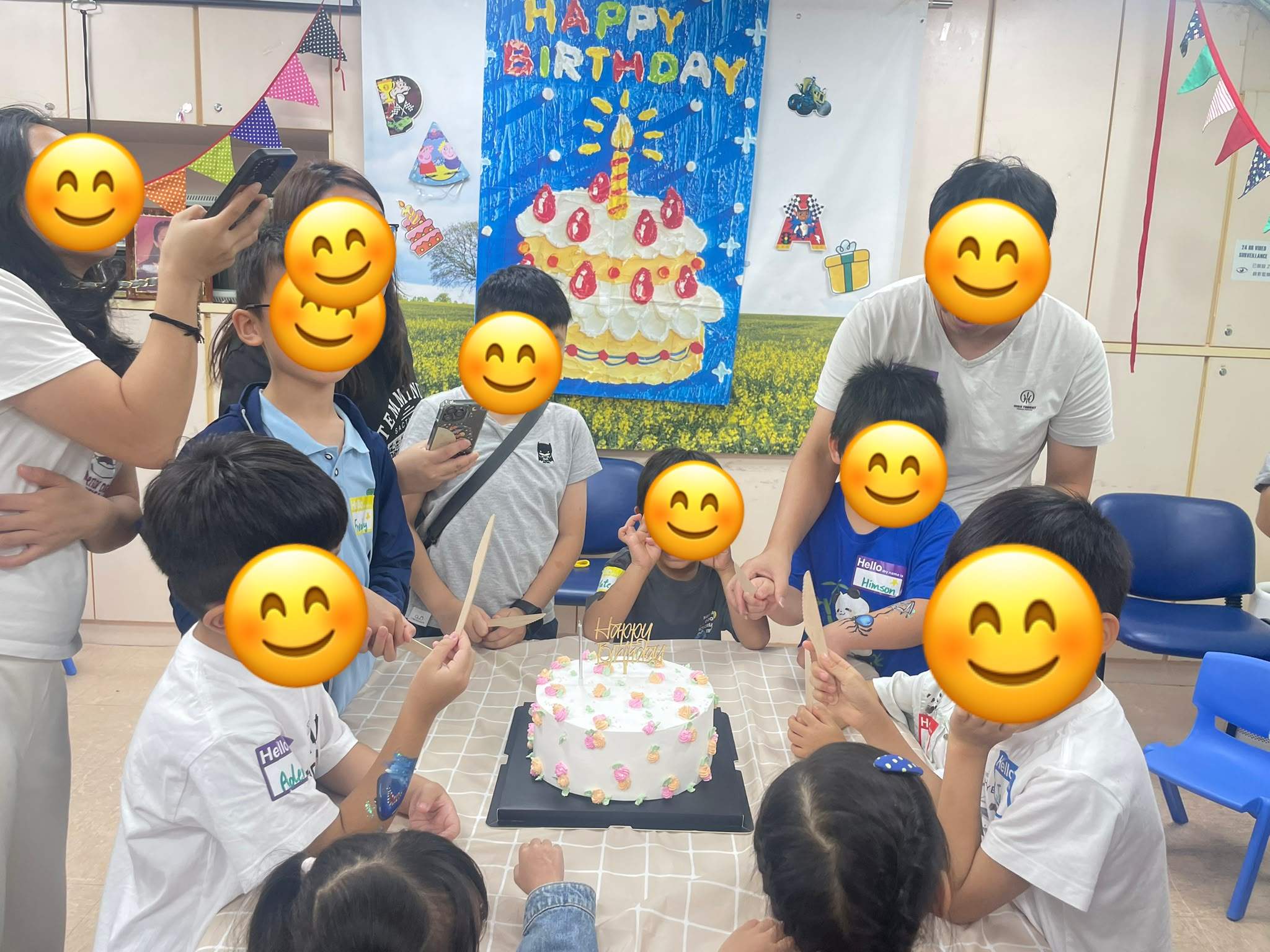 Children and adults gather around a decorated birthday cake.