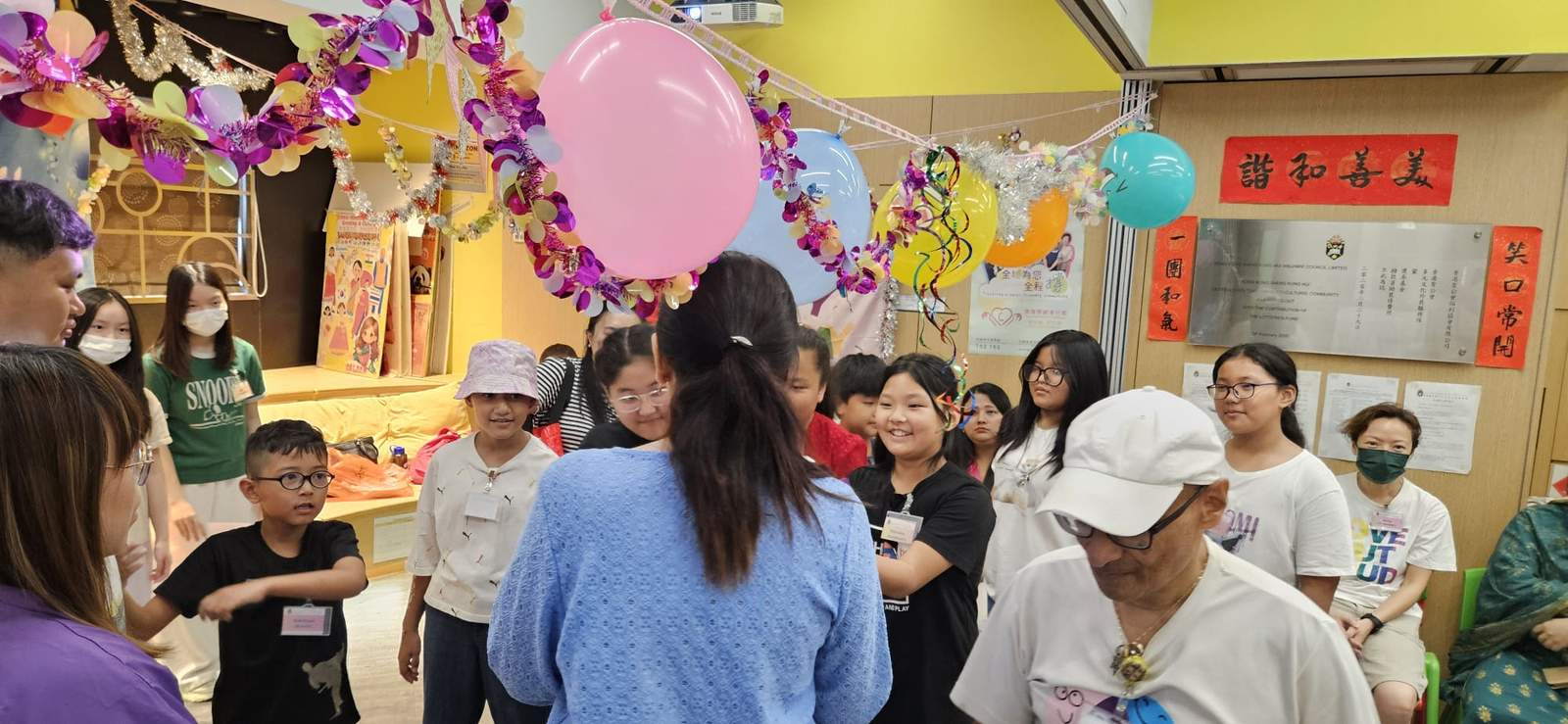 A group gathers beneath balloons during an indoor activity.