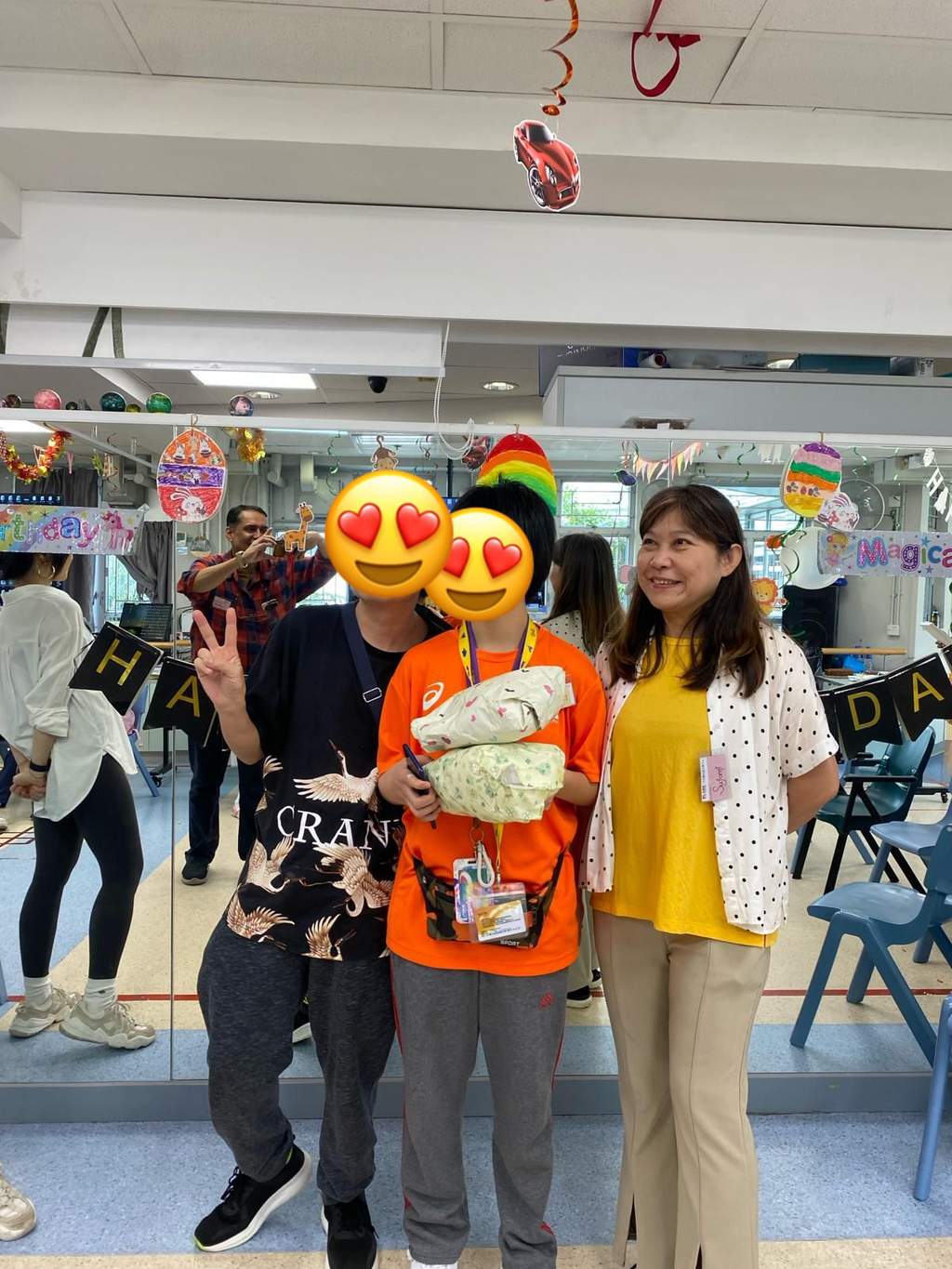 Three people pose together holding a wrapped gift.