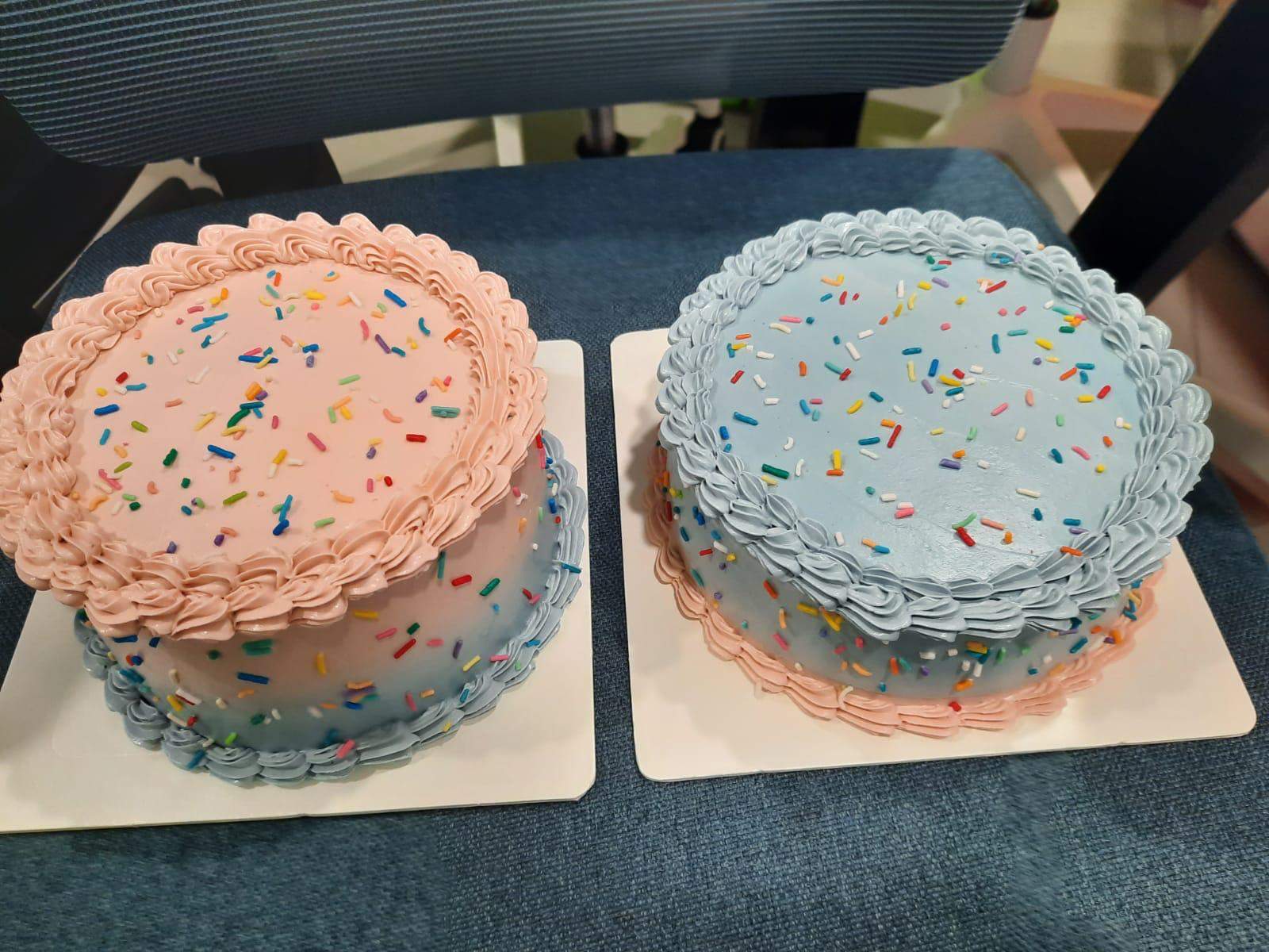 Two round frosted cakes sit side by side on a table.