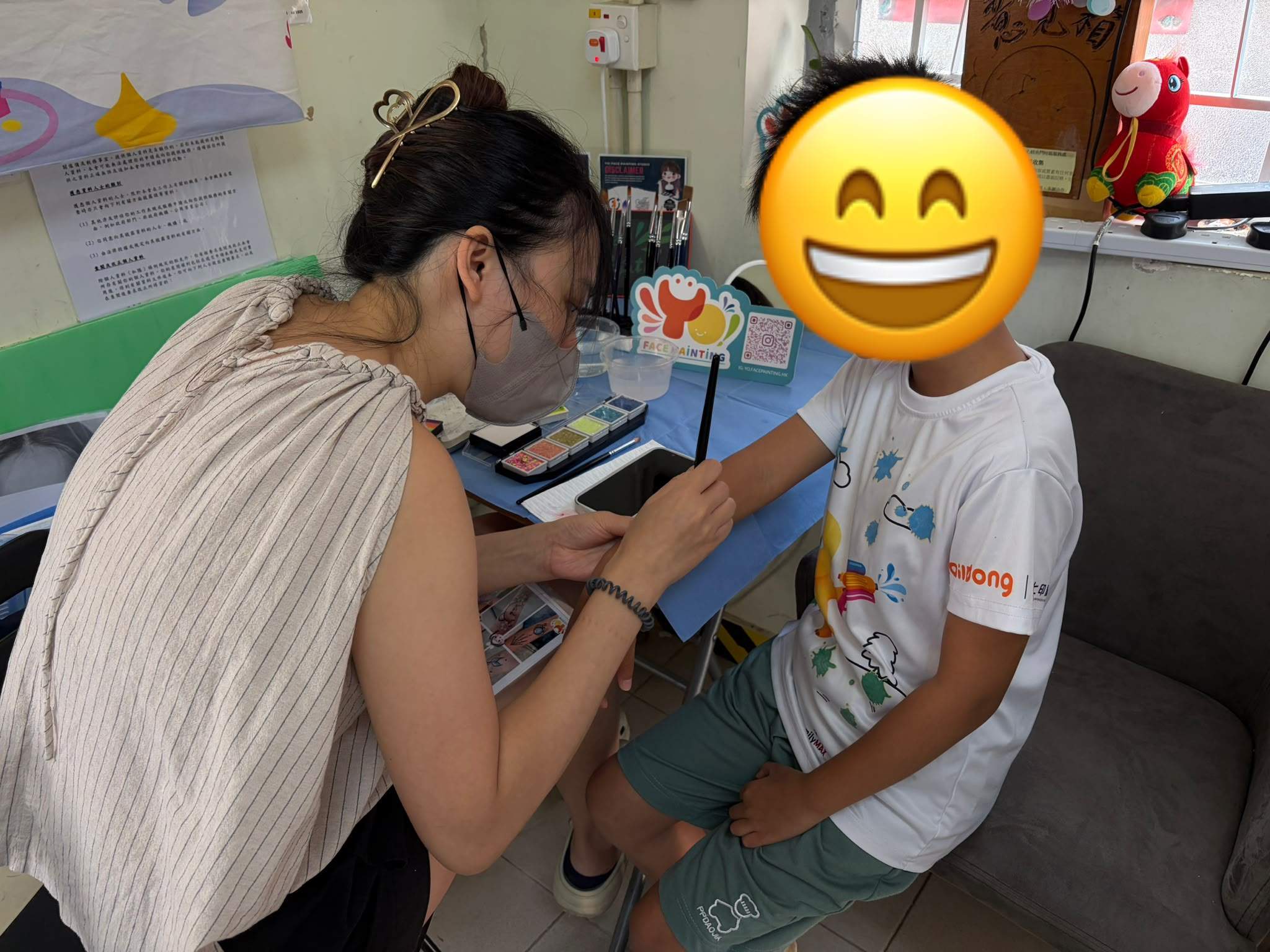 A face painter applies a design to a child’s forearm.