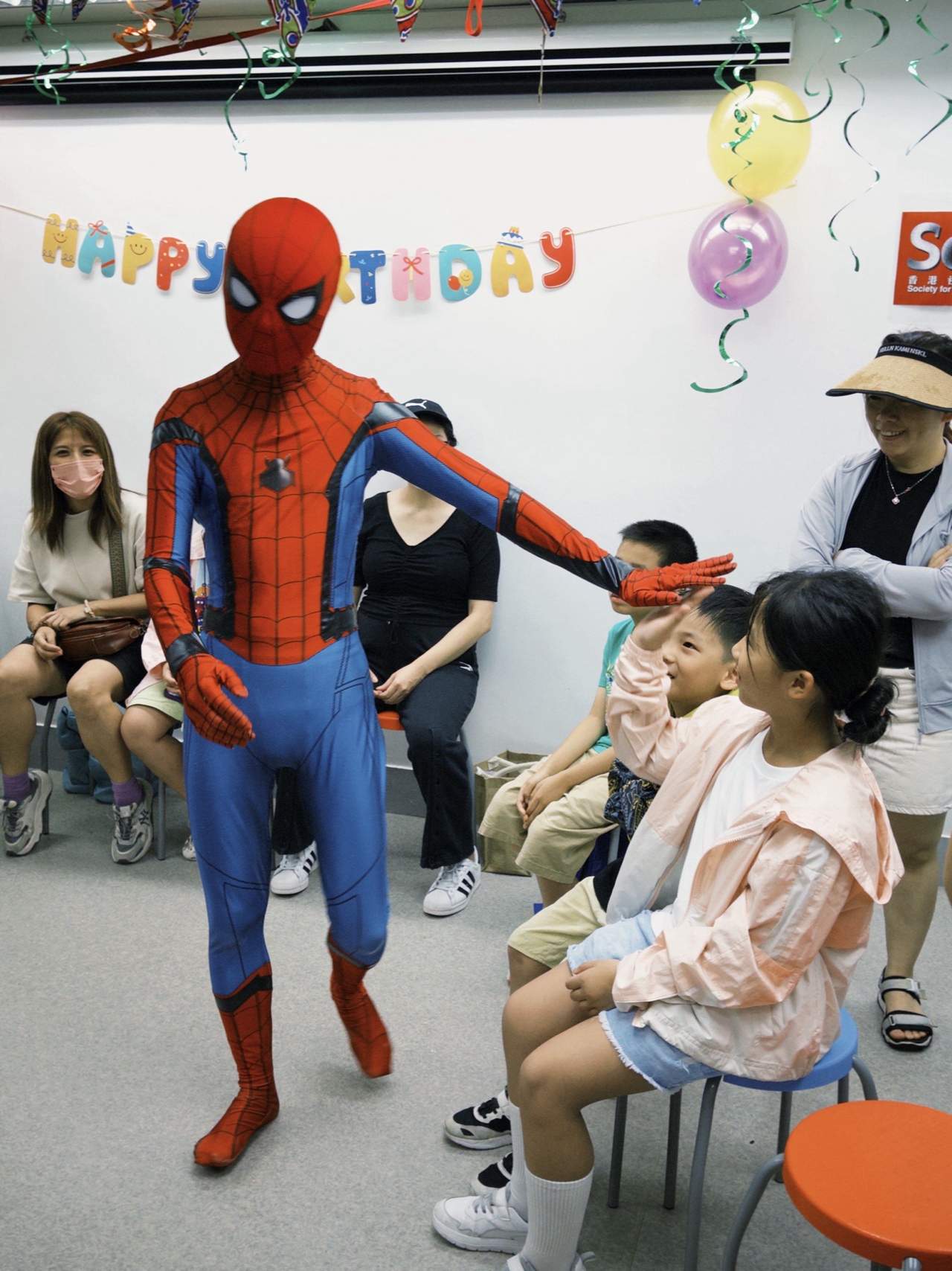 A costumed performer entertains children seated along the walls.