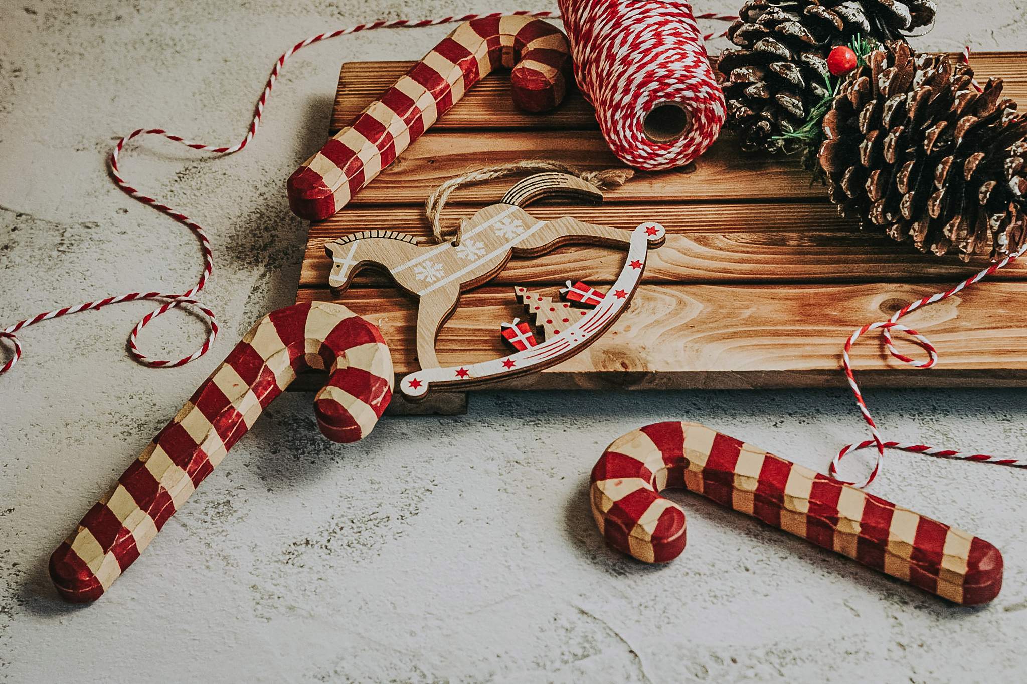 Candy canes, pinecones, ribbon, and a wooden horse decorate rustic boards.